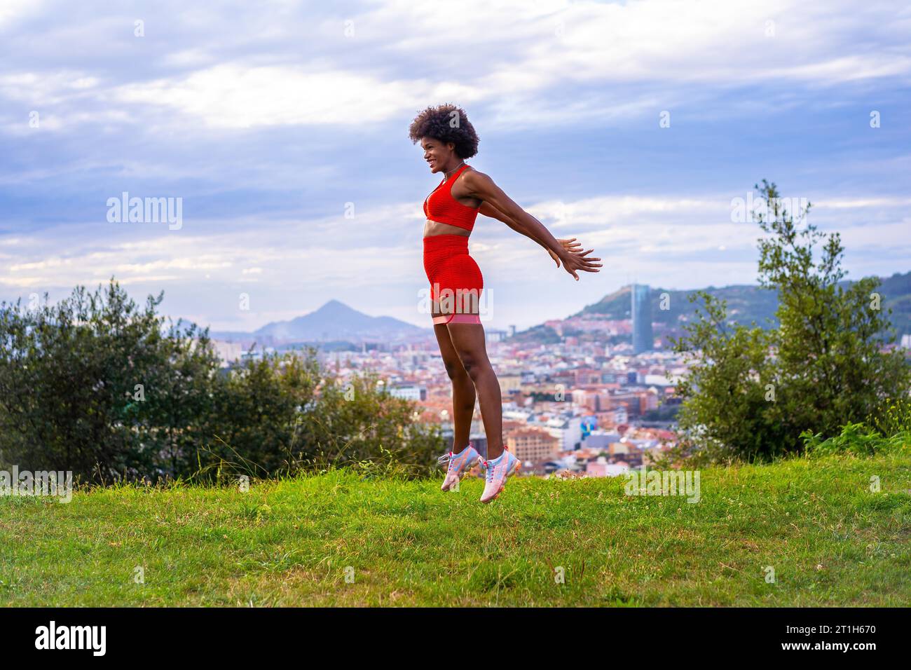 Fitness with a young black girl with afro hair, doing jumps and squats ...