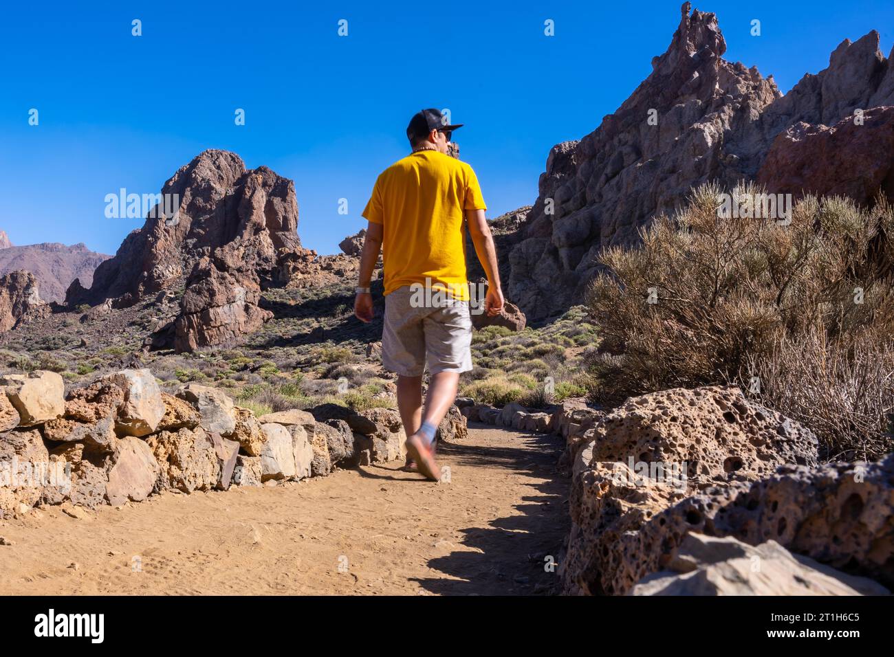A tourist walking next to the Roques de Gracia and the Roque Cinchado in the natural area of Teide in Tenerife, Canary Islands Stock Photo