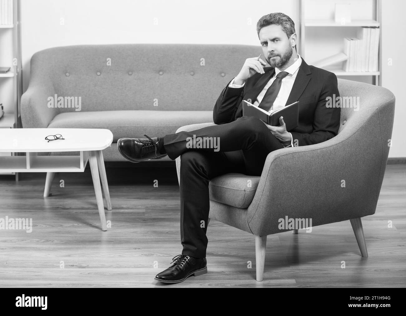 mature boss in suit sit in office making notes in notebook. Stock Photo