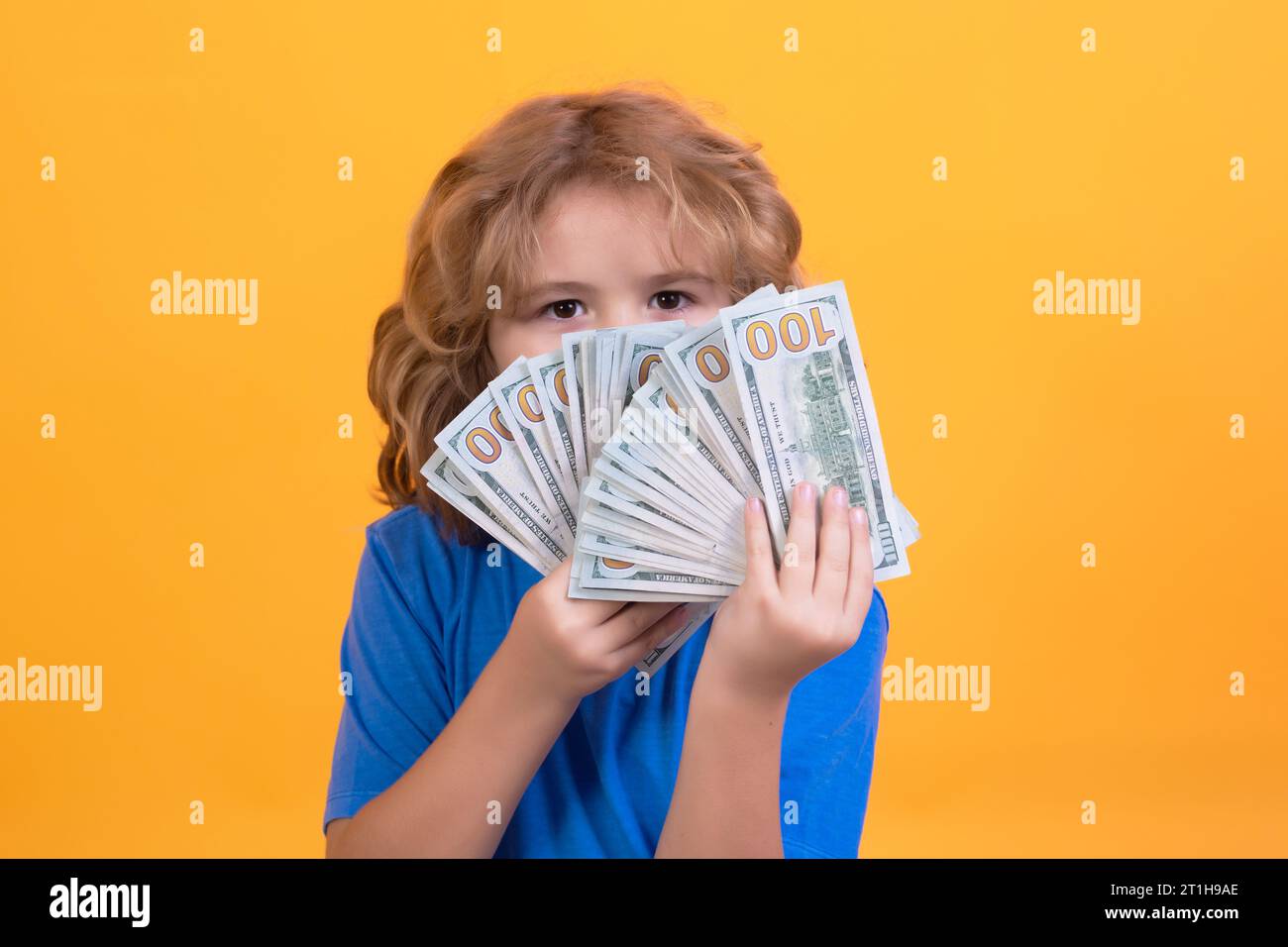 Child having a lot of hundred dollars isolated on yellow background Stock Photo