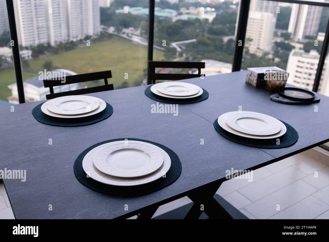 A restaurant with a view of the city, consisting of modern chairs and a dark table.  Stock Photo