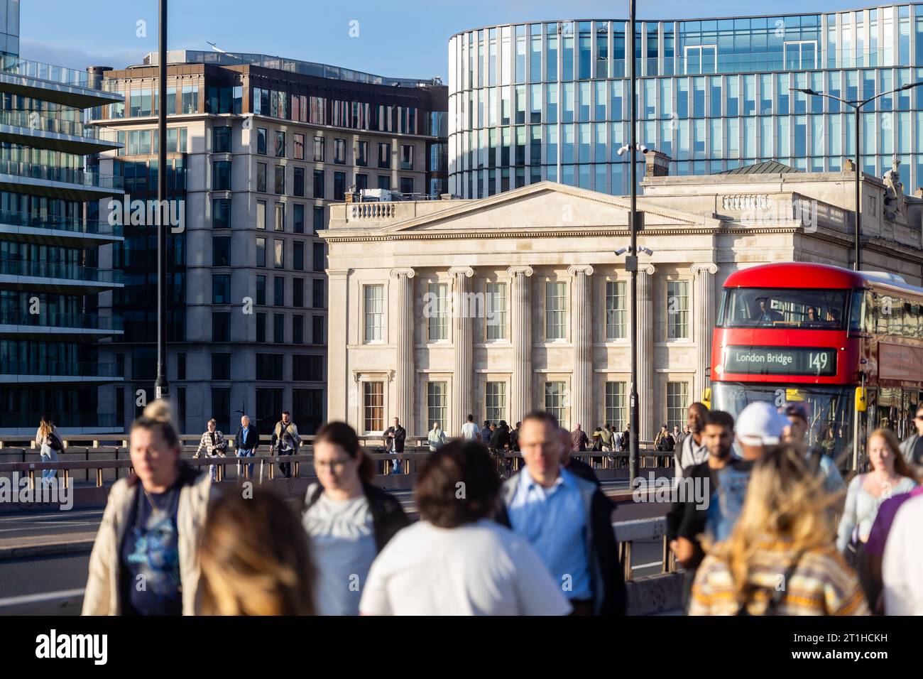 Unrecognizable people are walking over London Bridge, Fishmonger's Hall in the background. Stock Photo