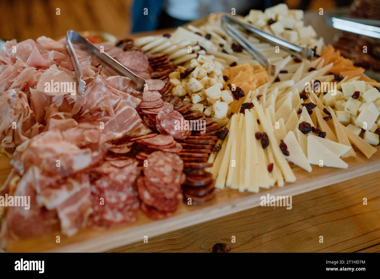 A wooden serving platter filled with a variety of meats and cheeses Stock Photo