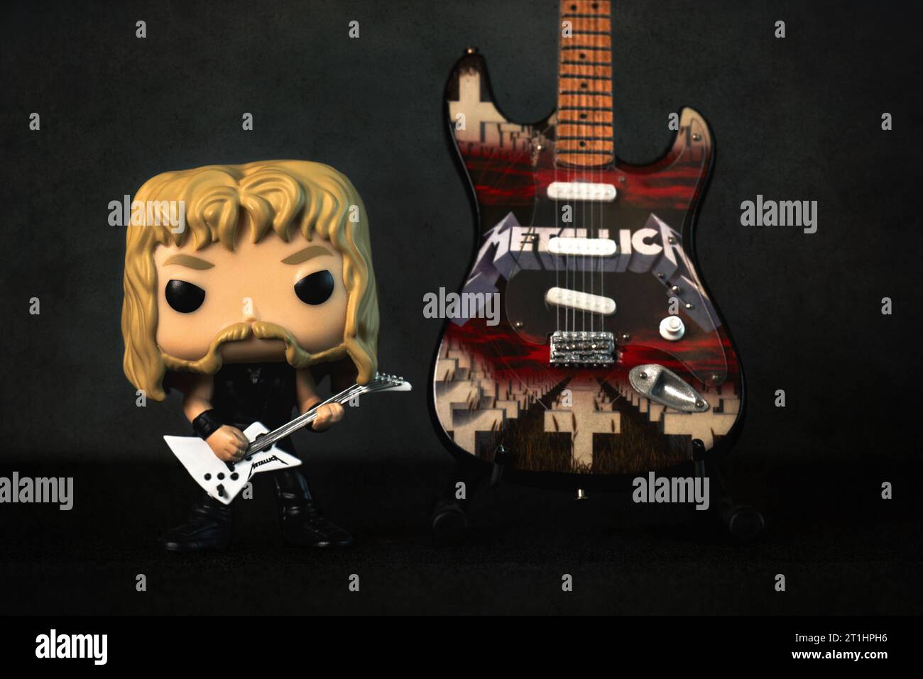 Funko POP vinyl figure of James hetfield singer of the american heavy metal group Metallica next to an electric guitar against dark background. Illust Stock Photo