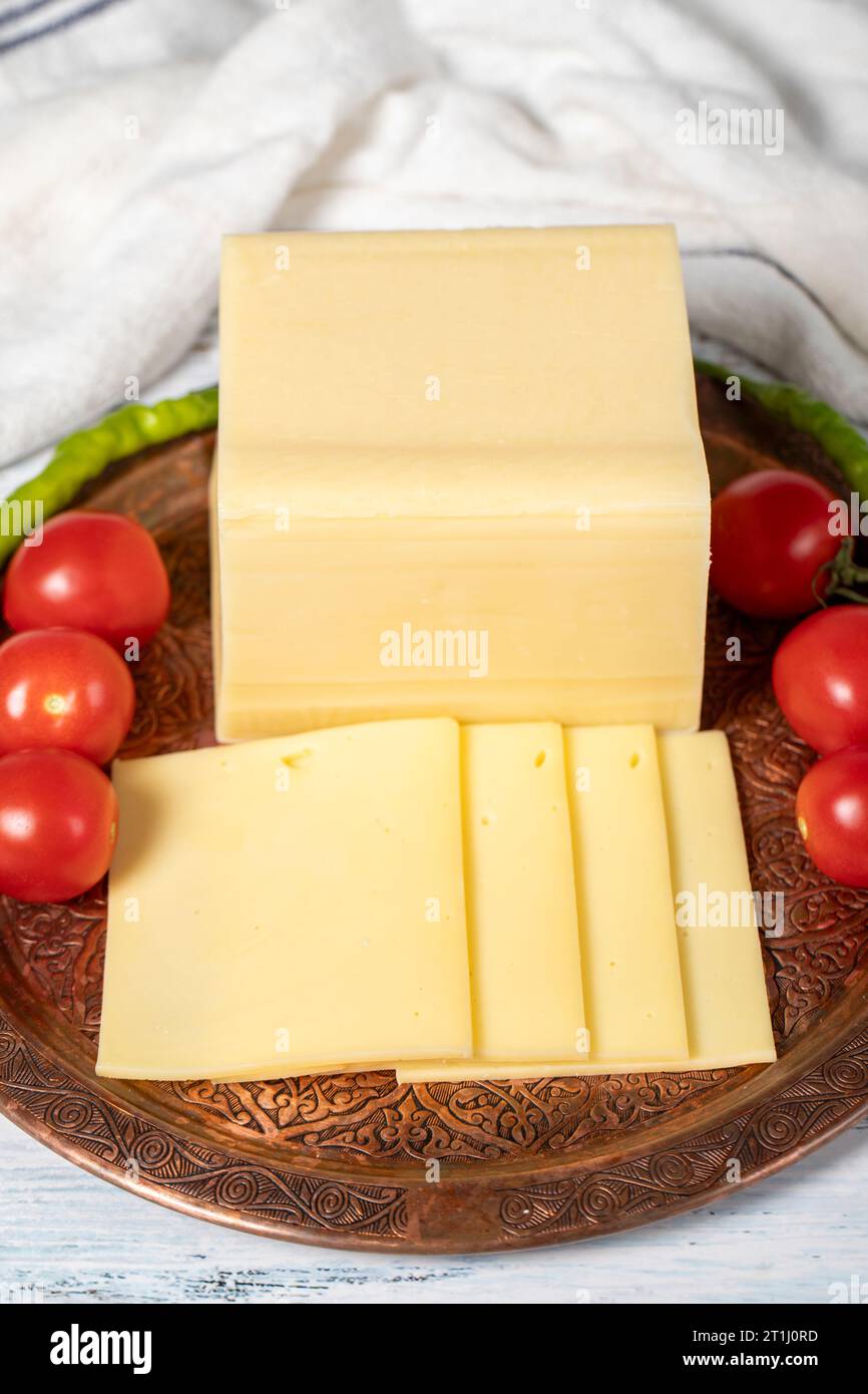 Fresh cheese or kashkaval in a copper plate. Fresh cheddar cheese on wooden background. local name kasar peyniri Stock Photo