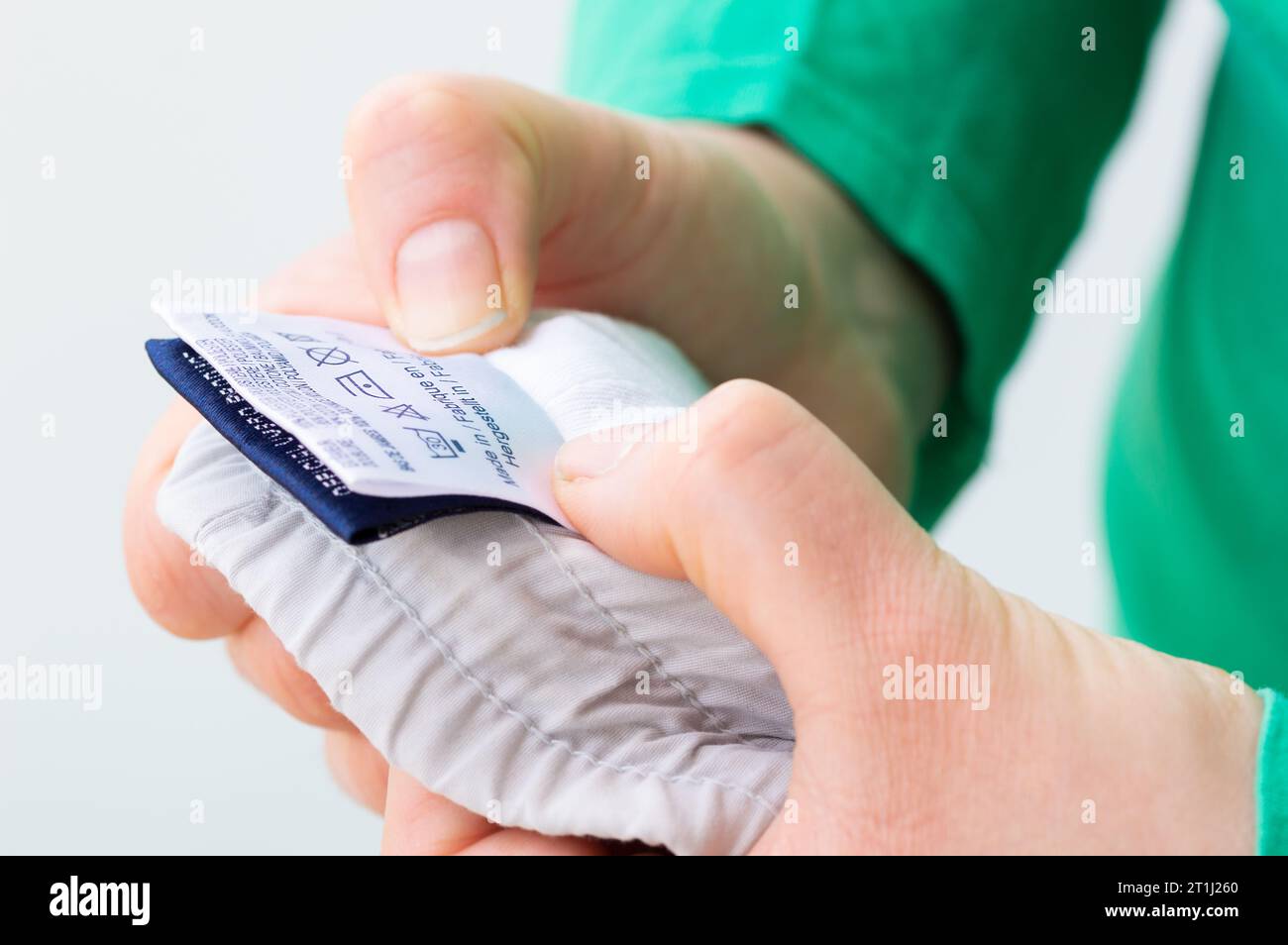 Close-up of person reading the clothing label showing washing instructions at home. Stock Photo
