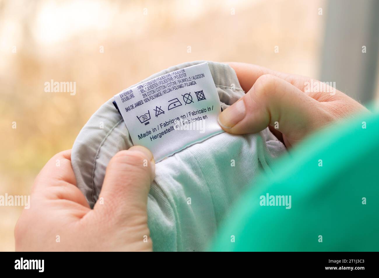 Close-up of person reading the clothing label showing washing instructions at home Stock Photo