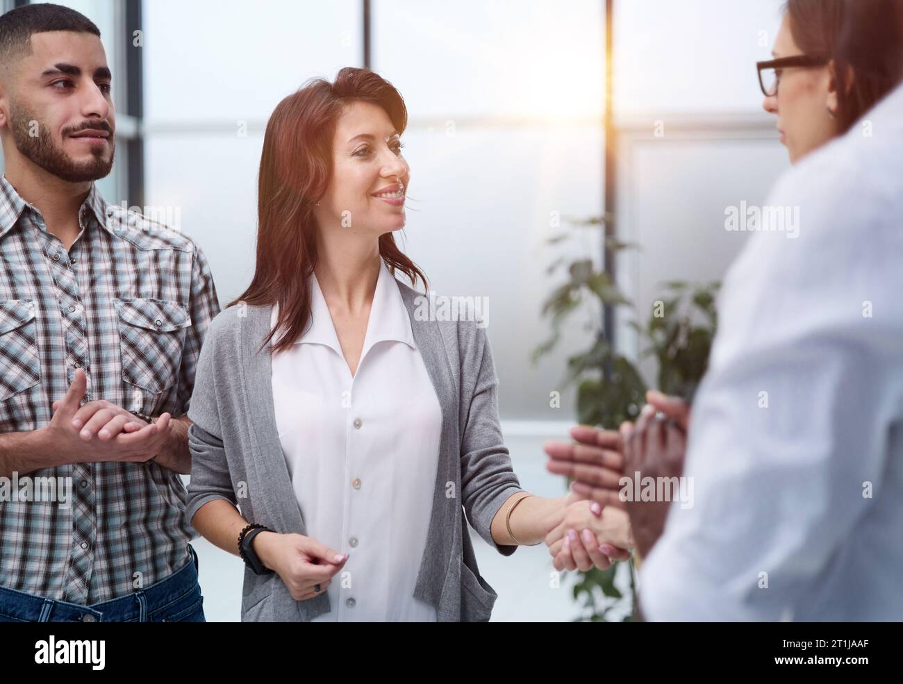 Business people standing and shaking hands in an office building Stock Photo