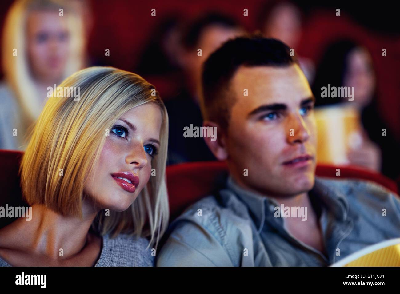 Cinema, movie and couple watching film, entertainment and popcorn on romantic evening together. Date night, man and woman in Hollywood theater with Stock Photo