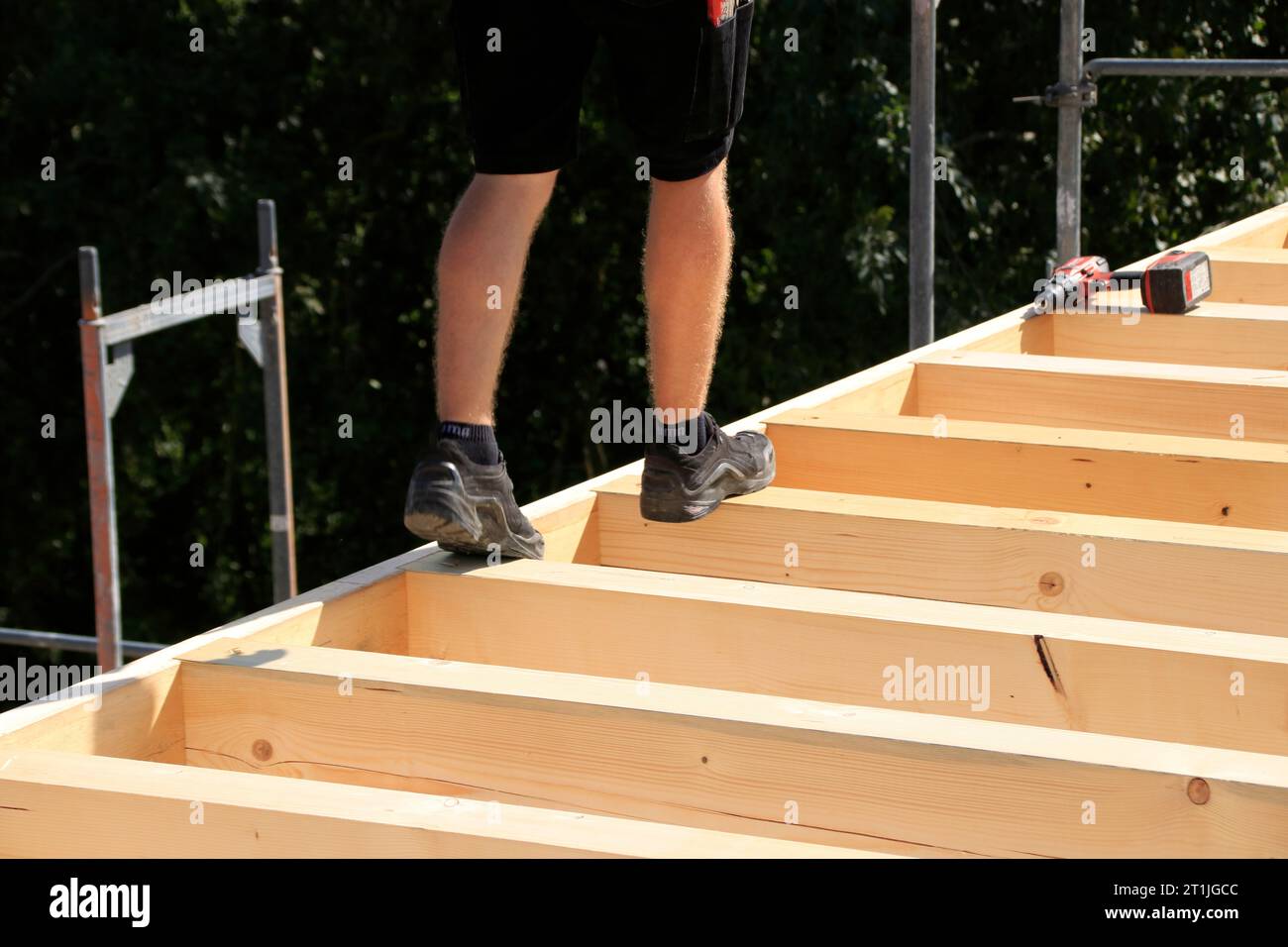 Carpenter walks across wooden beams on a roof Stock Photo