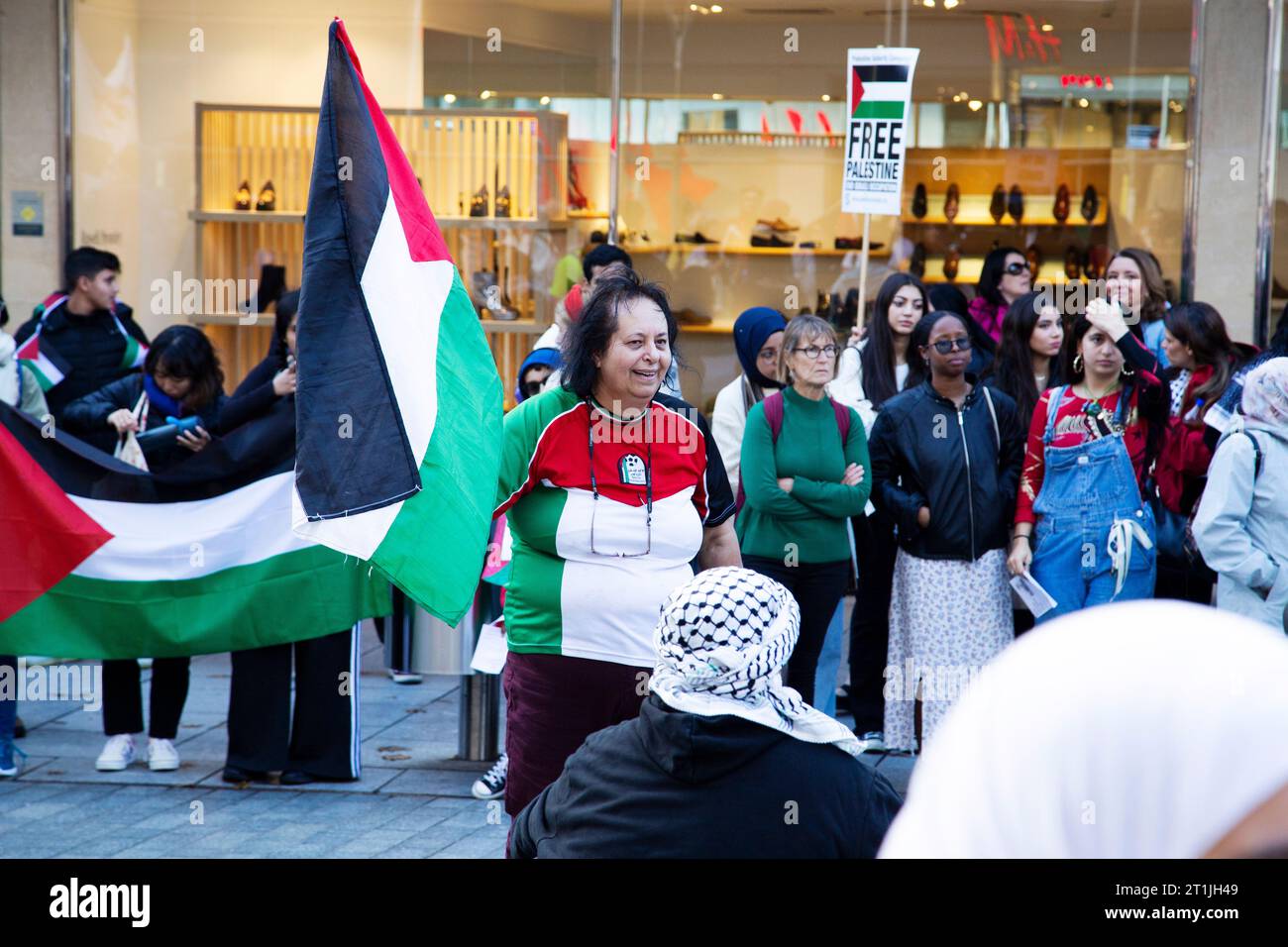 Free Palestine protest Exeter city centre - lady in centre of circle wearing Palestine football shirt Stock Photo