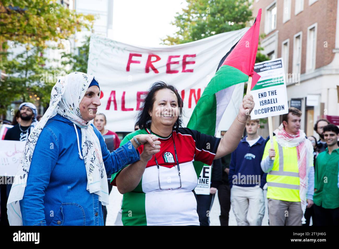 Free Palestine protest Exeter city centre - lady in Palestine football shirt holding hands with lady in head scarf Stock Photo