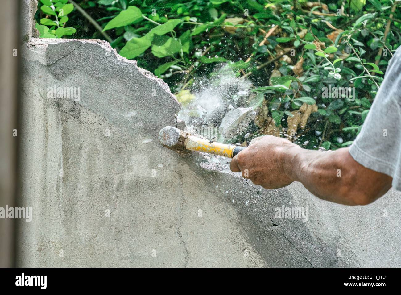 Hand of worker using hammer smashing and demolish on brick block wall
