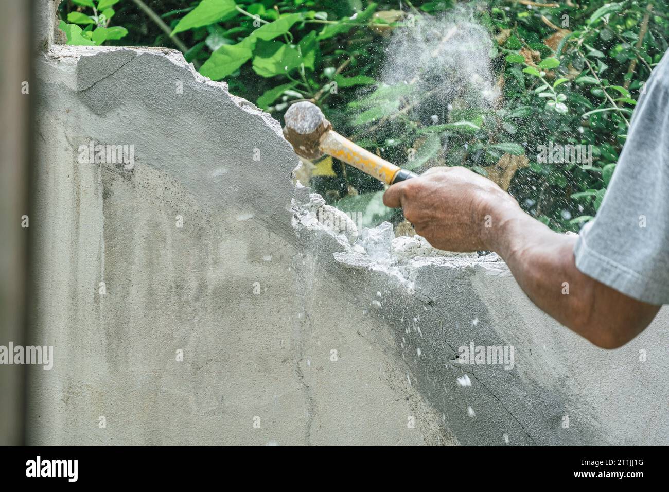 Hand of worker using hammer smashing and demolish on brick block wall