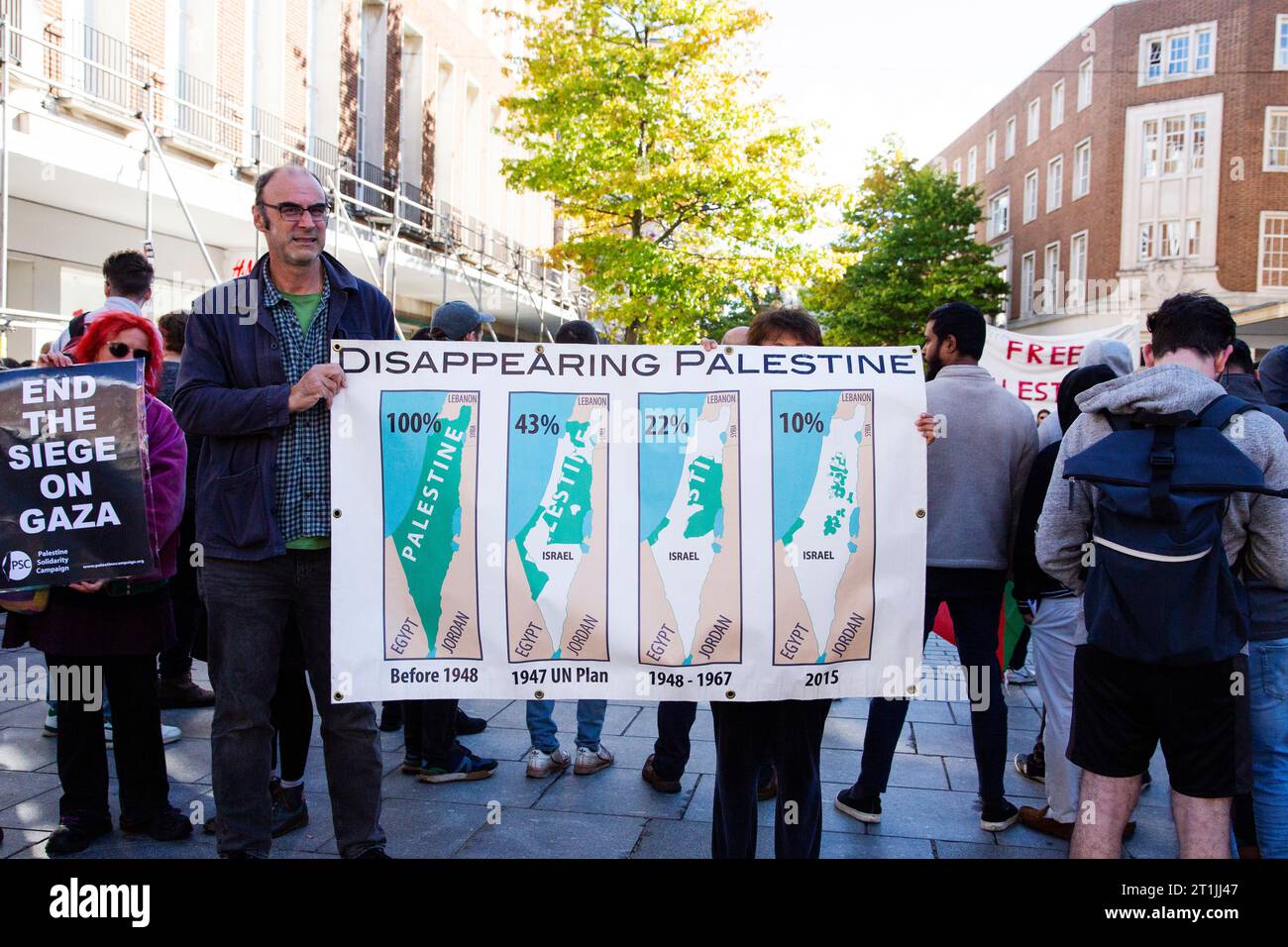 Free Palestine protest Exeter city centre - gentleman and hidden lady holding large 'disappearing Palestine' banner with map graphics and percentages Stock Photo