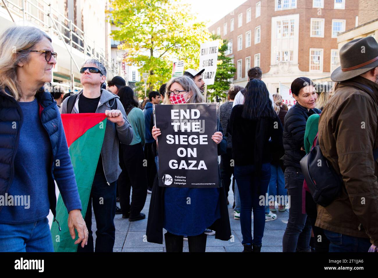 Free Palestine protest Exeter - masked lady holding 'end the siege on Gaza' black and white sign (Palestine solidarity campaign) Stock Photo
