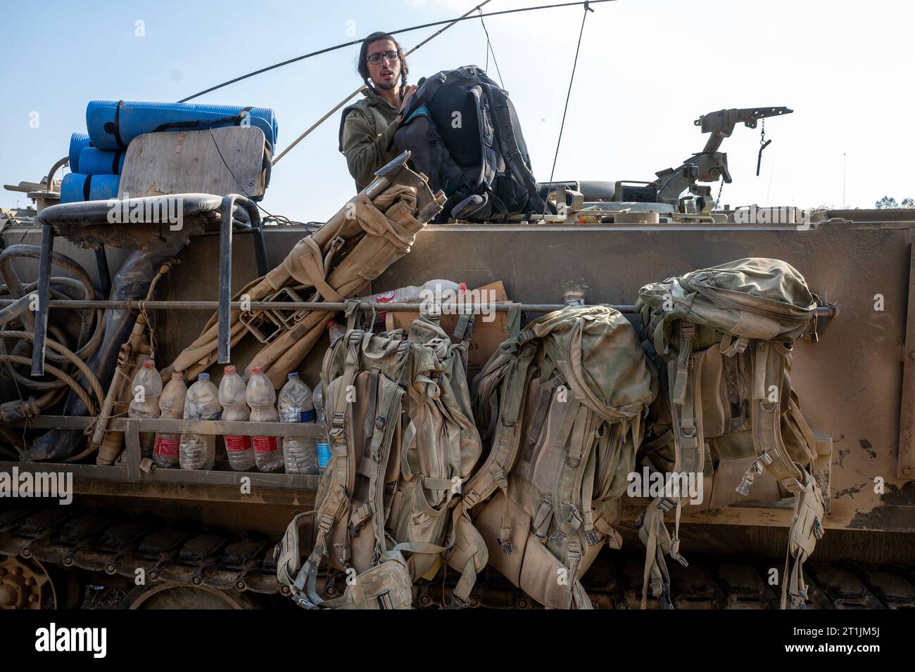 An Israeli Defense Forces (IDF) soldier arranges gear atop an Armored  Personnel Carrier in the staging area at Be'eri, close to the border with  the Gaza Strip on October 14, 2023. One
