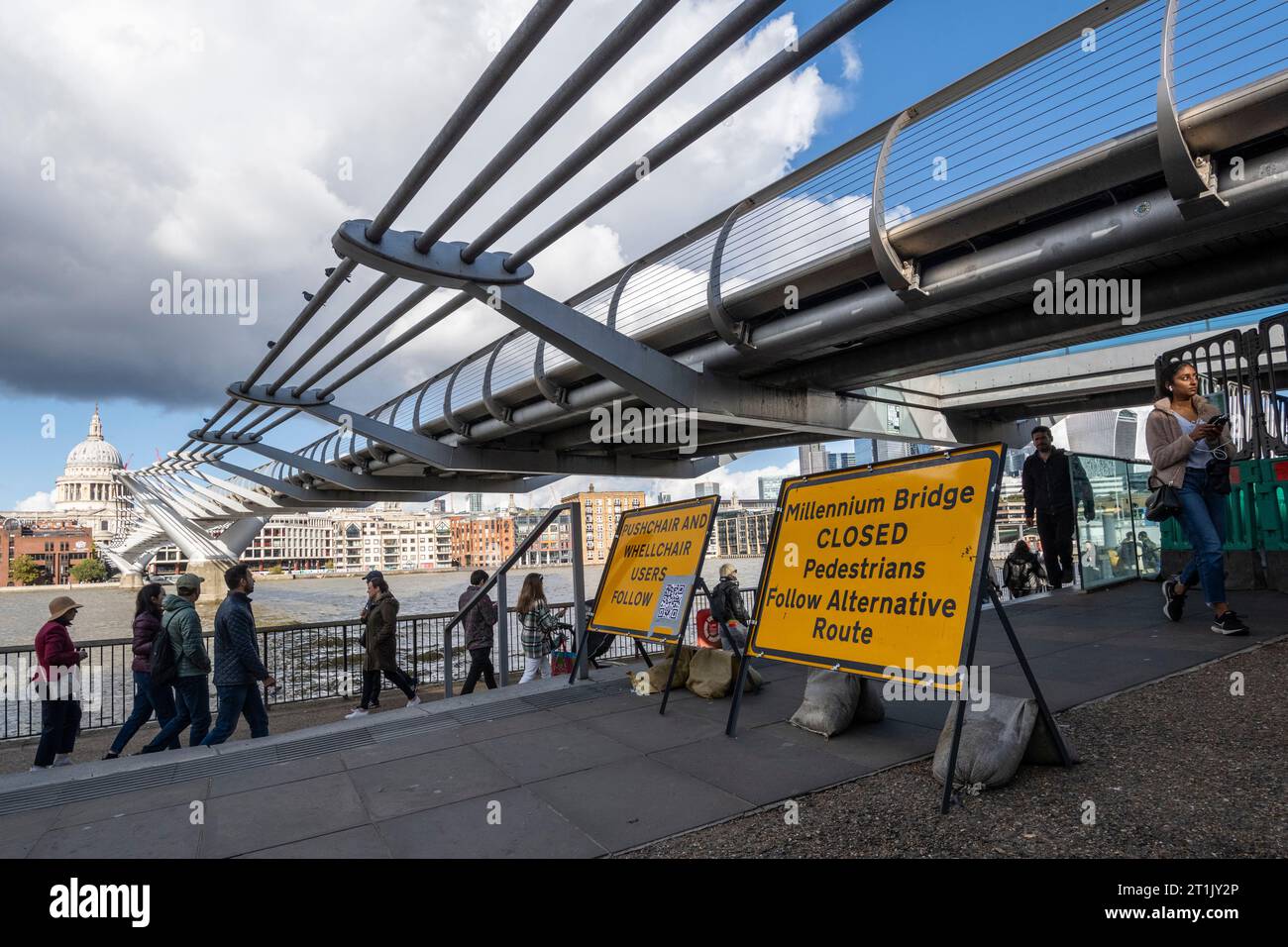 London, UK.  14 October 2023.  Members of the public pass signage informing them that the Millennium Bridge has closed for maintenance.  City Bridge Foundation, a charity that looks after London's major Thames crossings, says that a layer of membrane has started to degrade and needs replacing.  Repairs will take three weeks.  Credit: Stephen Chung / Alamy Live News Stock Photo
