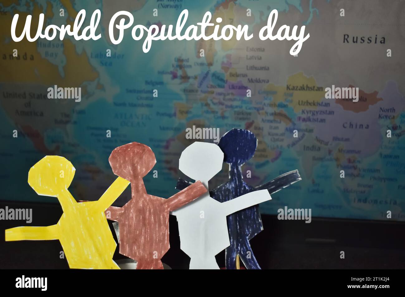A close up picture of various races people paper dolls in front of a word map. World population day concept Stock Photo