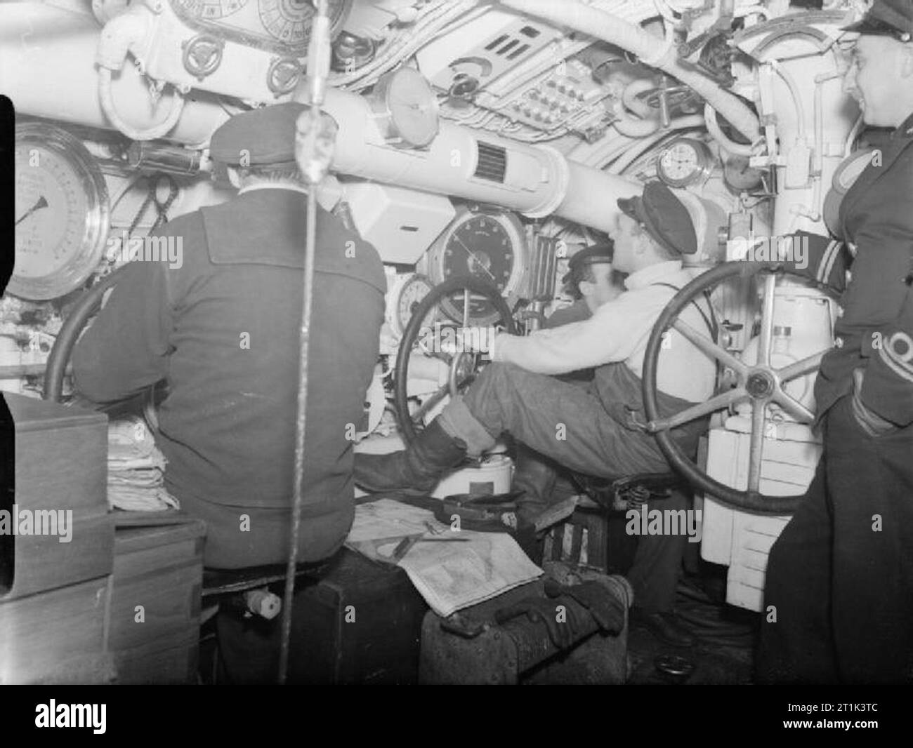 The Royal Navy during the Second World War The Central Control Room, from where diving and surfacing manoeuvres are controlled on board the Dutch submarine O 14. The Hydroplane helmsmen sit in front of their gauges depth-keeping. One of the depth gauges indicates 30 feet. The Chief Engineer is seen right, an Officer in Dutch Submarines, a Chief Petty Officer in British Vessels. Stock Photo