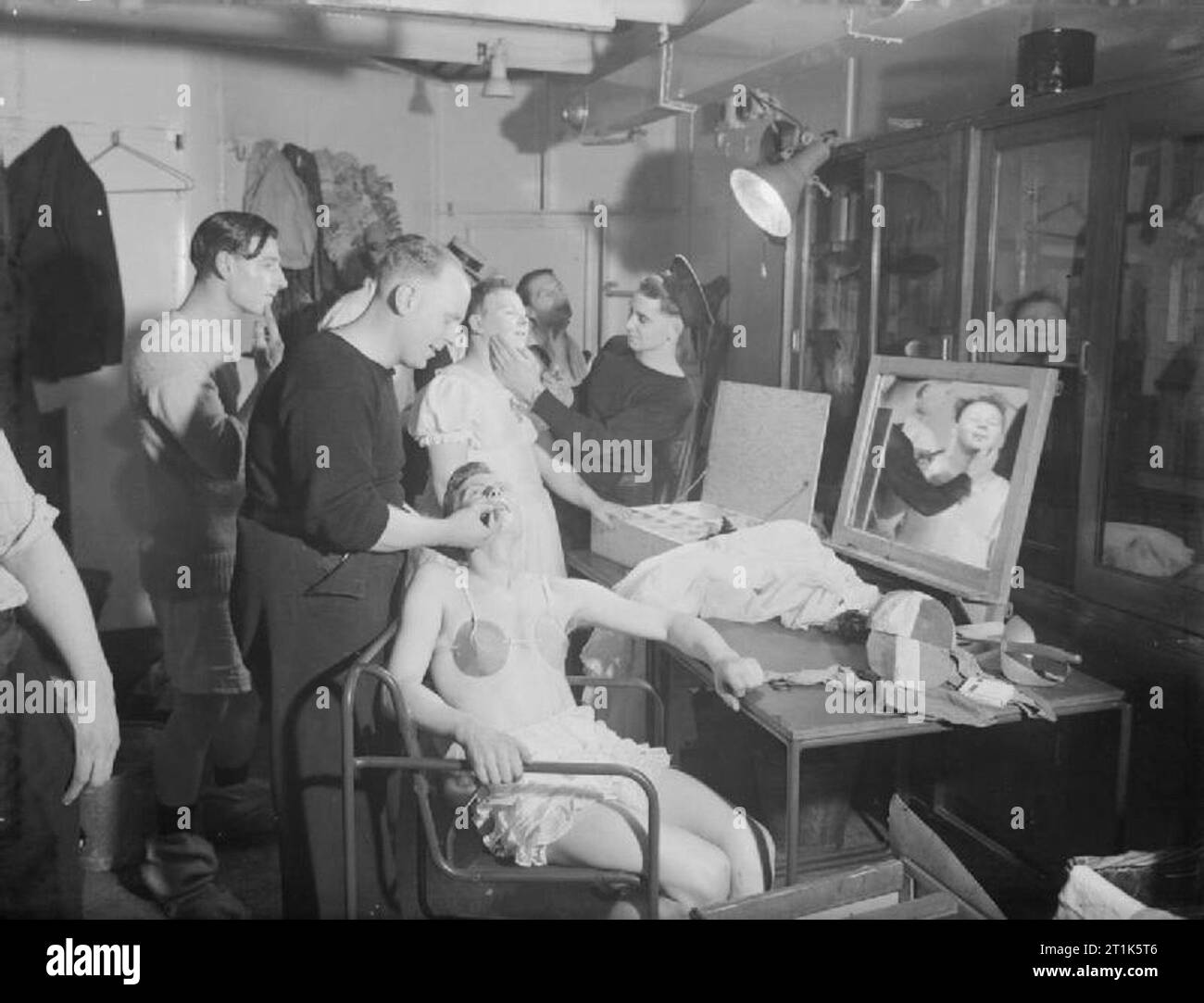 Leisure and Entertainment during the Second World War The Armed Forces: Sailors prepare a Christmas concert on board HMS TYNE at Scapa Flow. The absence of women on board usually required some performers to dress up as women. The picture shows the cast's female impersonators donning costumes and applying make up. Nearest the camera, Leading Stoker R C Wright making up Stoker A J Barnes, while in the background, Stoker F Dickinson being made up by Stoker A Hills. Stock Photo
