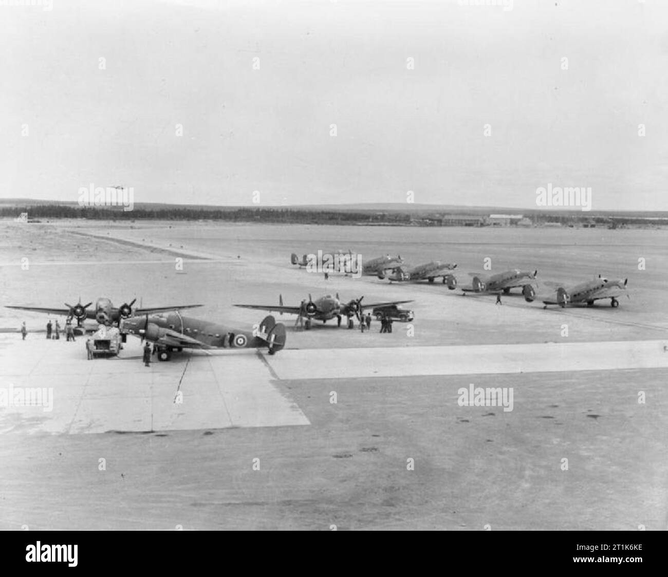 Royal Air Force Ferry Command, 1941-1943. Lockheed Hudson Mark IIIs are prepared for their trans-Atlantic ferry flights at Gander, Newfoundland. At left, one is being refuelled for the journey while two aircraft facing the camera undergo engine checks. Five aircraft facing the runway are ready for the flight and a final Hudson can be seen about to land after flying from the main Ferry Command airport at Dorval, Ontario. Stock Photo