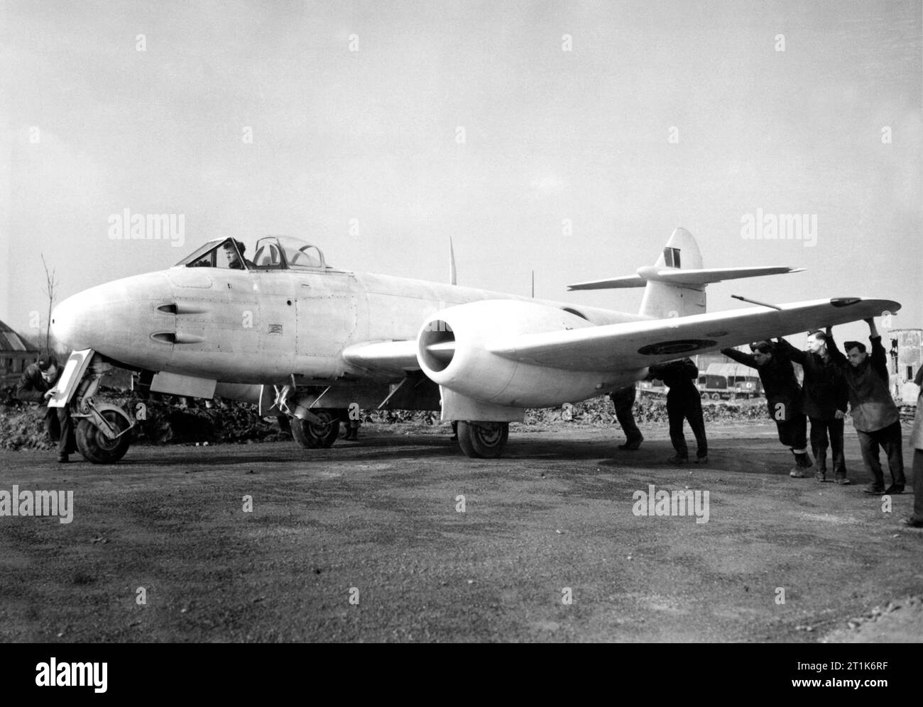 Ground crew manhandle a Gloster Meteor F.3 of the 616 Squadron Detachment at B58/Melsbroek, Belgium, on 6 February 1945. The aircraft had deployed to the Continent to counter the threat of the German Me262 jet fighter which had started to enter service with the Luftwaffe. The Meteor was the first British jet fighter and the Allies' only jet aircraft to achieve combat operations during the Second World War. The Meteor first flew in 1943 and commenced operations on 27 July 1944 with No. 616 Squadron RAF. Some of these images have had some dodging and burning done and have been retouched to remov Stock Photo