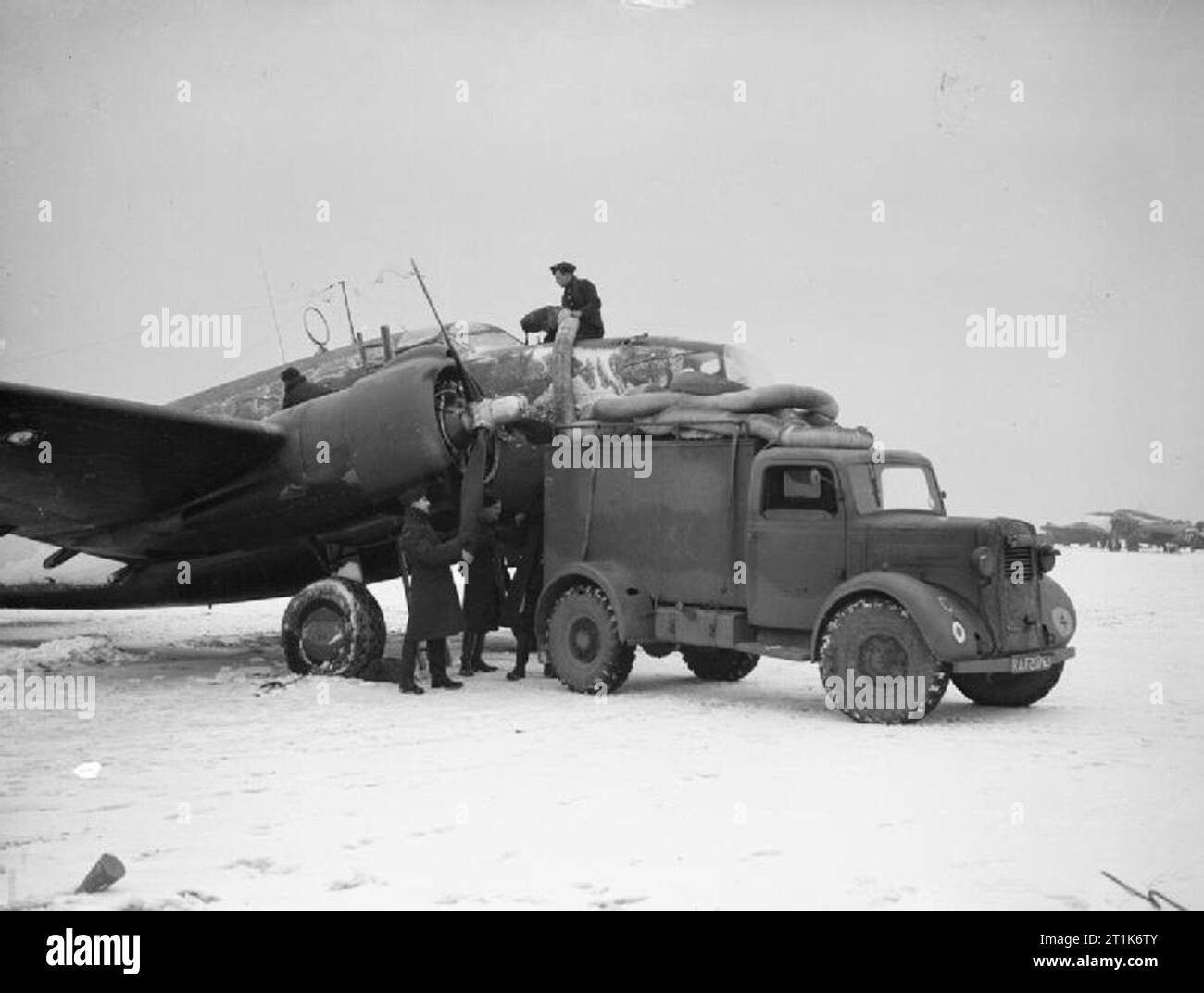 Royal Air Force 1939-1945- Coastal Command Ground staff prepare a No. 233 Squadron Hudson for flight in freezing conditions at Thorney Island, 19 January 1942. The 'hot air van' has been brought in to warm up the engines and de-ice the cockpit windscreen. Stock Photo
