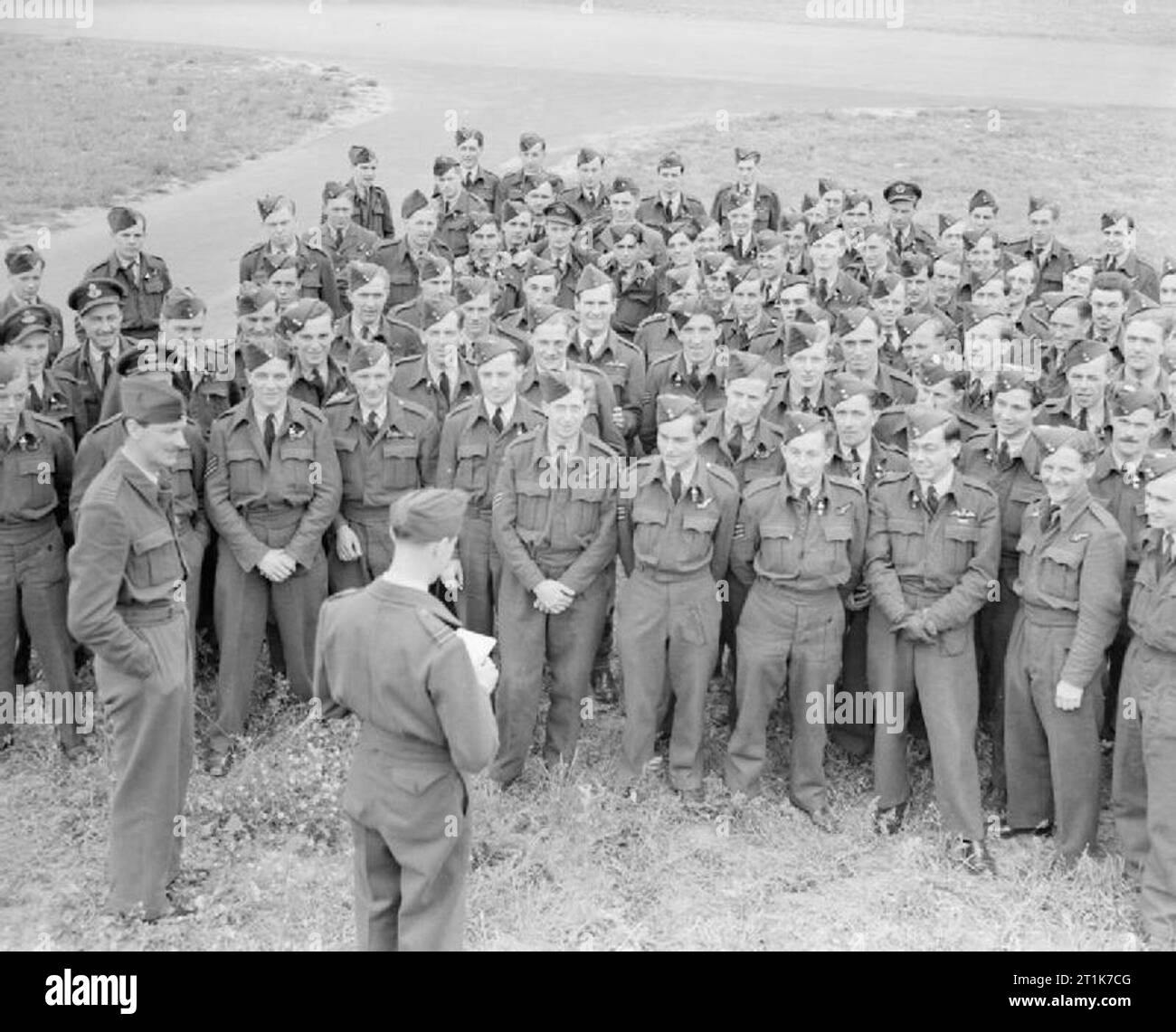 Royal Air Force 1939-1945- Bomber Command Watched by the CO, Wing Commander D A Gardner (left), aircrew of No 166 Squadron at Kirmington, Lincolnshire, gather on 20 July 1944 to hear the Adjutant, Flight Lieutenant F C Tigh, read out a congratulatory message from Field Marshal Montgomery, thanking the bomber crews for their efforts supporting the British Second Army's armoured offensive in Normandy, Operation 'Goodwood'. Stock Photo