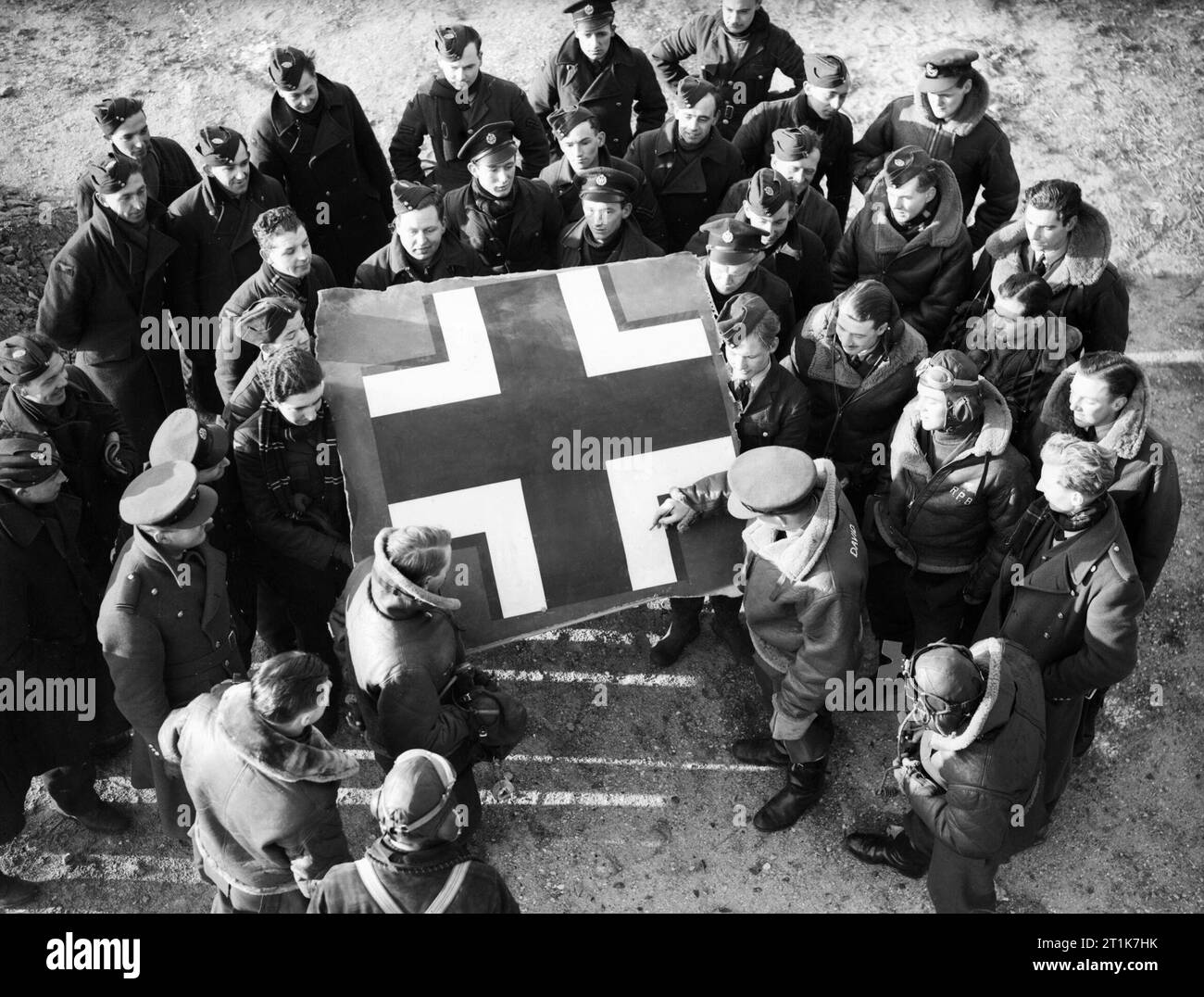 Royal Air Force 1939-1945- Fighter Command Pilots and ground crew gather around the fuselage Balkenkreuz from No 87 Squadron's first kill, a Heinkel He111 shot down by Flight Lieutenant Robert Voase-Jeff on 2 November 1939. Pilot Officer Dennis David, who damaged another Heinkel on the same day, autographs the trophy. Watching on the right is a new member of the squadron, Pilot Officer Roland Beamont (in flying helmet, with initials on his Irvin flying jacket), a future ace and famous postwar test-pilot. Stock Photo