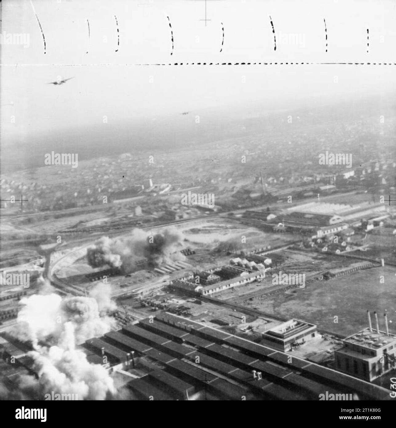 Royal Air Force Bomber Command, 1942-1945. Low-level oblique aerial photograph taken during the course of a daylight attack on the Matford automotive works at Poissy, France, by Douglas Bostons of Nos. 88 and 226 Squadrons RAF. This special raid, led by the Commanding Officer of 226 Squadron, Wing Commander V S Butler, opened the 1942 day-bombing offensive. 12 aircraft were despatched, of which 8 successfully bombed the target. Here, two Bostons can be seen running in towards the target as bombs fall on lines of finished lorries, and smoke from exploding bombs pours from the factory roof (lowe Stock Photo