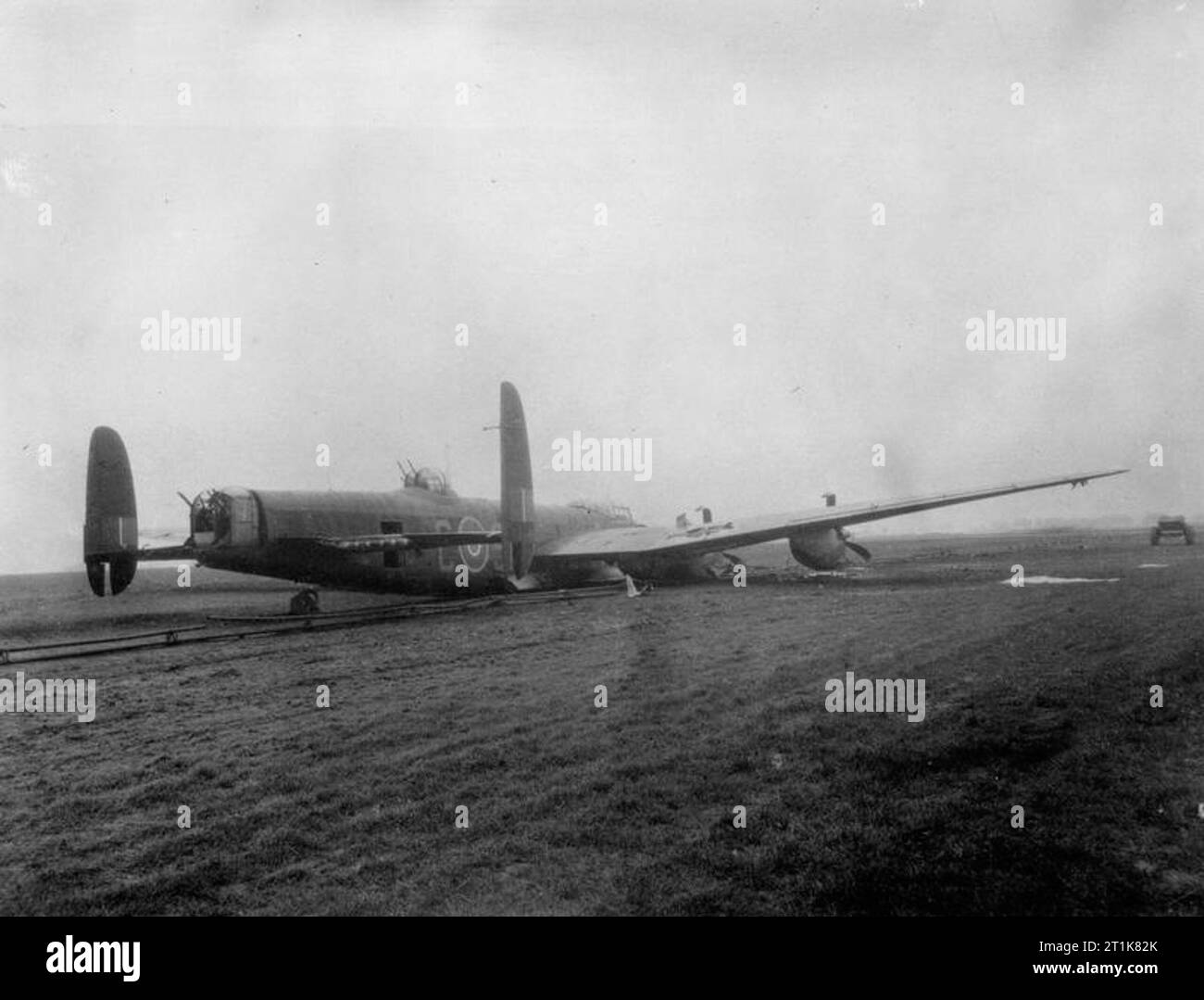 Royal Air Force Bomber Command, 1942-1945. Avro Lancaster B Mark I, ME590 'SR-C', of No. 101 Squadron RAF, lies on the FIDO (Fog Investigation and Dispersal Operation) pipework at Ludford Magna, Lincolnshire, after a successful crash-landing on returning from a raid to Augsburg on the night of 25/26 February 1944. The aircraft was damaged by anti-aircraft fire, which disabled the hydraulic system and holed the starboard fuel tank, and was also attacked by a Messerschmitt Bf 110 night fighter which set it on fire and wrecked the elevators. In spite of the damage the pilot, Sergeant R Dixon, bro Stock Photo
