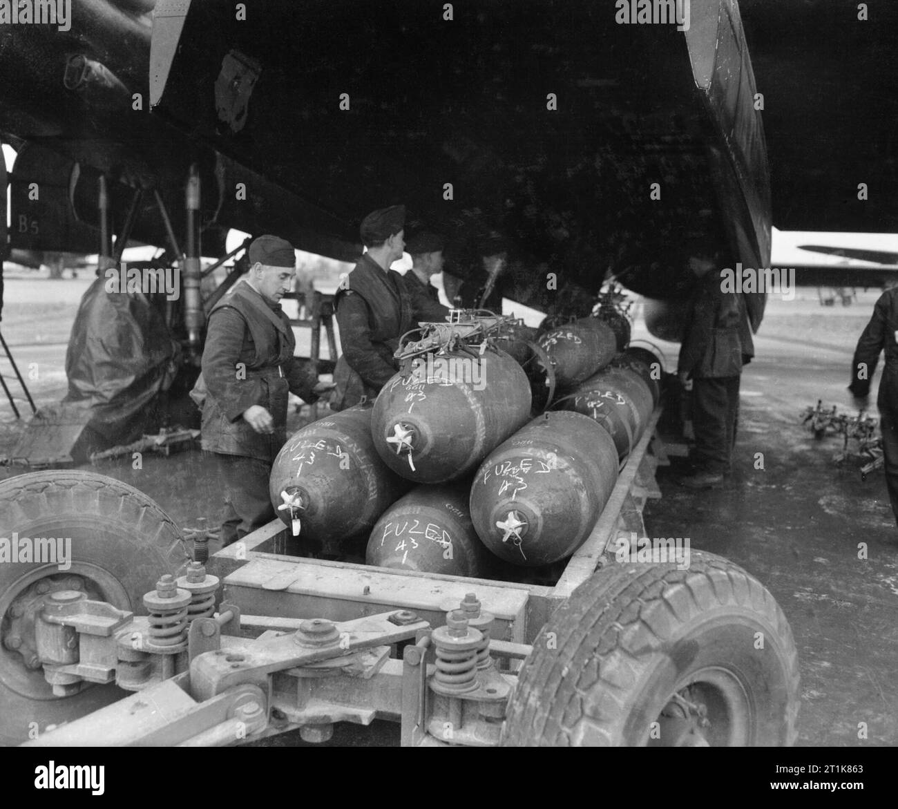Royal Air Force Bomber Command, 1942-1945. Armourers prepare to load 1,000-lb MC bombs into the bomb-bay of an Avro Lancaster B Mark III of No. 106 Squadron RAF at Metheringham, Lincolnshire, for a major night raid on Frankfurt, Germany. The chalk markings on the bombs indicate that each has been fuzed with a No. 43 air-armed nose pistol, the safety pins of which can be seen hanging from the nose rotor. These will be removed shortly before the crew board the aircraft. Stock Photo