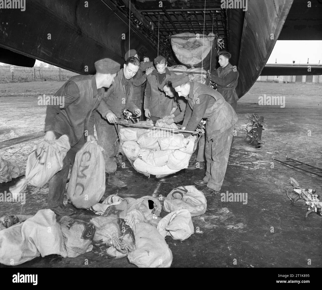 Royal Air Force Bomber Command, 1942-1945. Operation MANNA. Ground crew loading food supplies into slings for hoisting into the bomb bay of an Avro Lancaster of No. 514 Squadron RAF at Waterbeach, Cambridgeshire. Between 29 April and 7 May 1945, Lancasters of Bomber Command dropped 6,672 tons of food to the starving populace of a large area in Western Holland still in German hands. Stock Photo