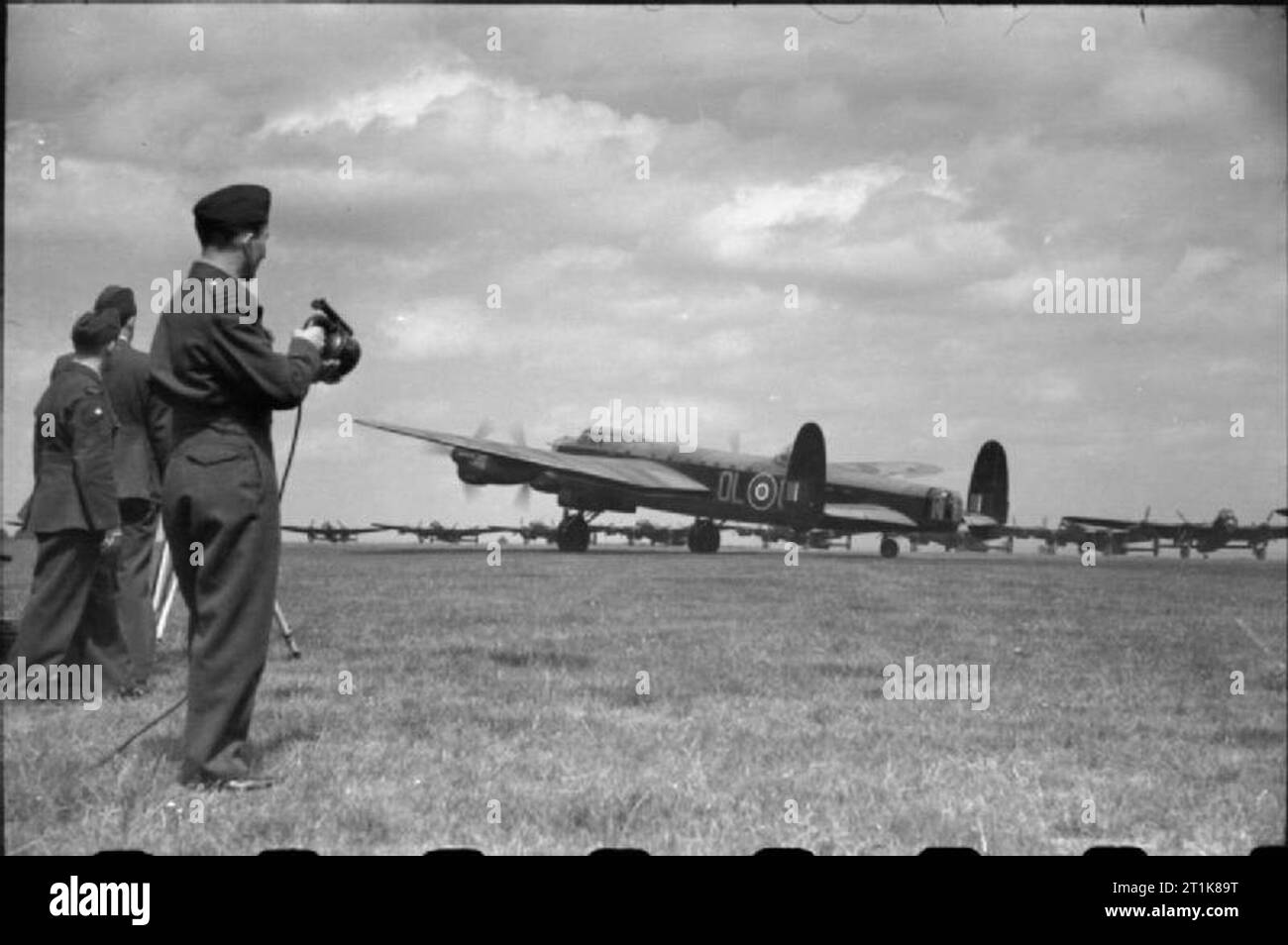 Royal Air Force Bomber Command, 1942-1945. An Avro Lancaster B Mark I of No. 83 Squadron RAF is signalled off on the third 'Thousand Bomber' raid, an attack on Bremen, Germany from Scampton, Lincolnshire. The Wing Commander (Flying) gives a green light for take off with his Aldis lamp. Stock Photo