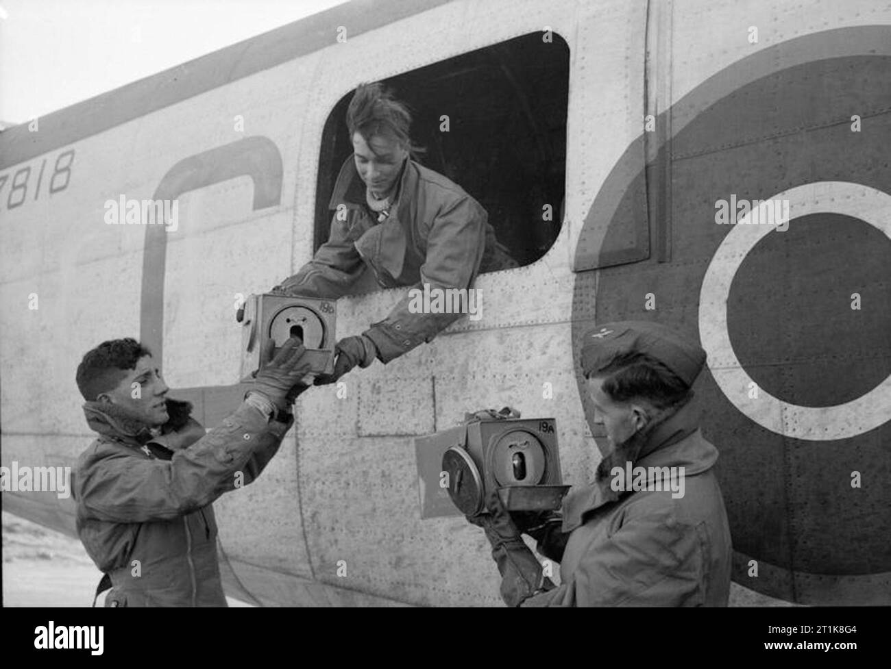 Royal Air Force Coastal Command, 1939-1945. Crewmen of Consolidated Liberator GR Mark VA, BZ818 'C', of No. 53 Squadron RAF handling carriers containing homing pigeons at St Eval, Cornwall, after a patrol over the Bay of Biscay. Sergeant J Knapp of Toronto, Canada, (in the hatchway) hands a carrier to Sergeant W Tatum of London, while Warrant Officer A Mackinnon of Auckland, New Zealand, holds a second carrier. Stock Photo