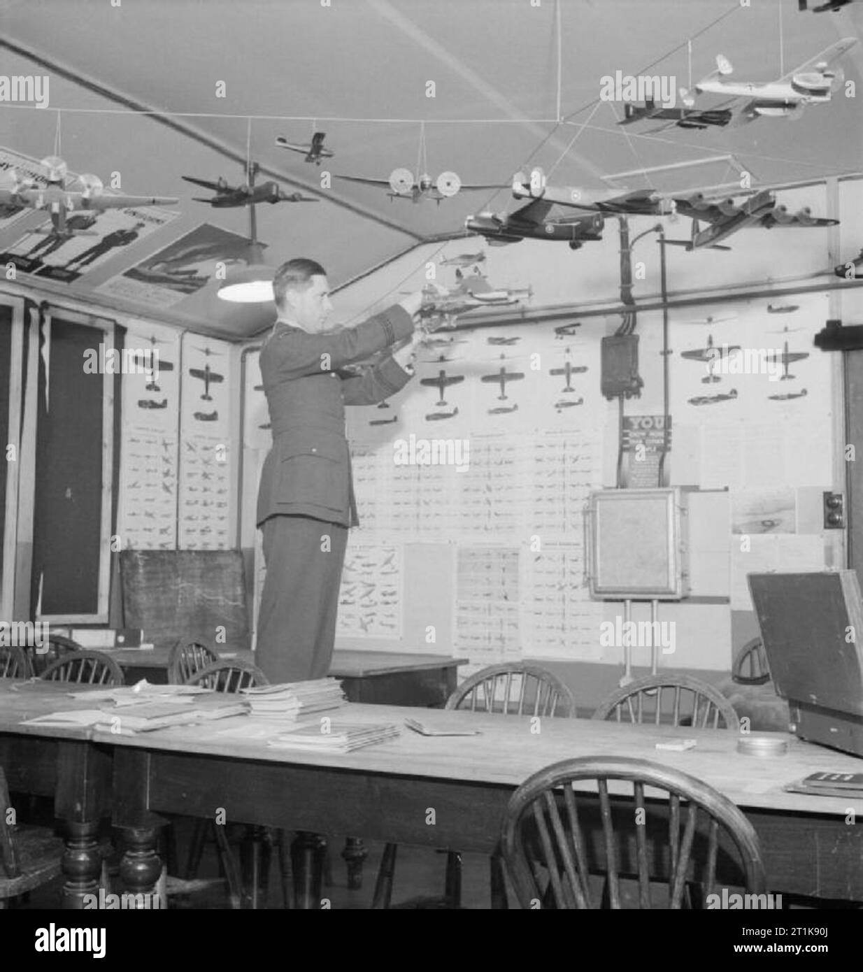 Royal Air Force Fighter Command, 1939-1945. Flight Lieutenant J M Maclennan, the Intelligence Officer of No. 406 Squadron RCAF, hanging aircraft recognition models in his office at Acklington, Northumberland. Stock Photo