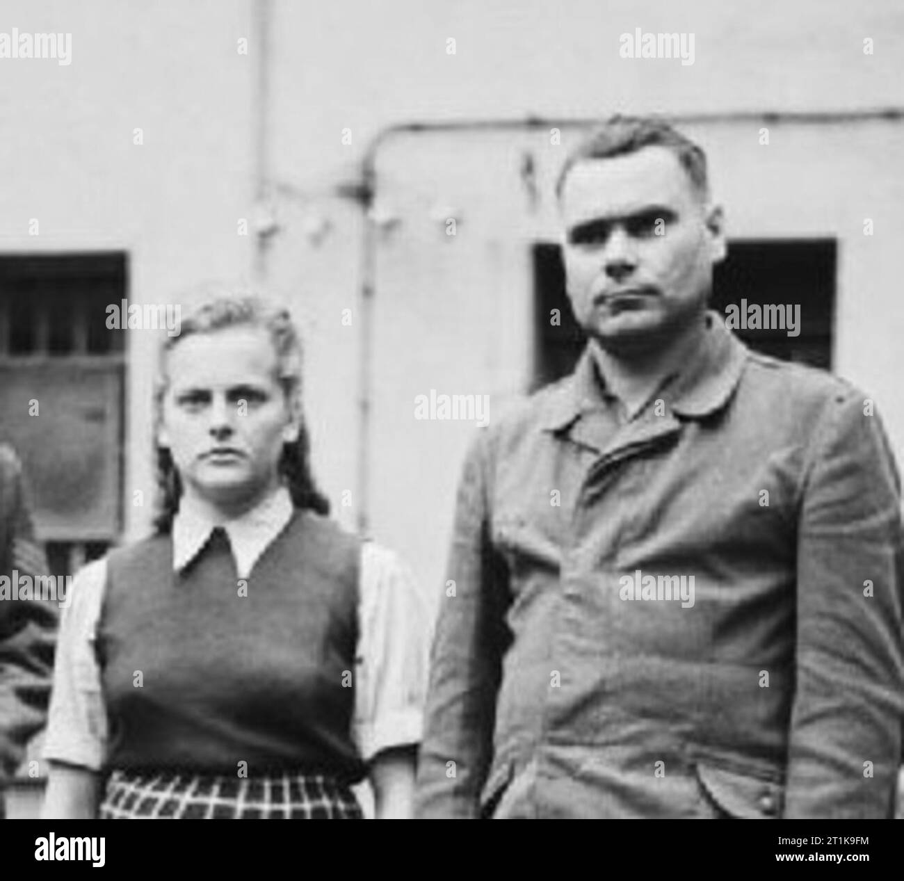 The Liberation of w:Bergen-Belsen concentration camp 1945 - Portraits of Belsen Guards at Celle Awaiting Trial, August 1945 w:Irma Grese standing in the courtyard of the Prisoner of War cage at Celle with w:Josef Kramer. Both were convicted of war crimes and sentenced to death. Stock Photo