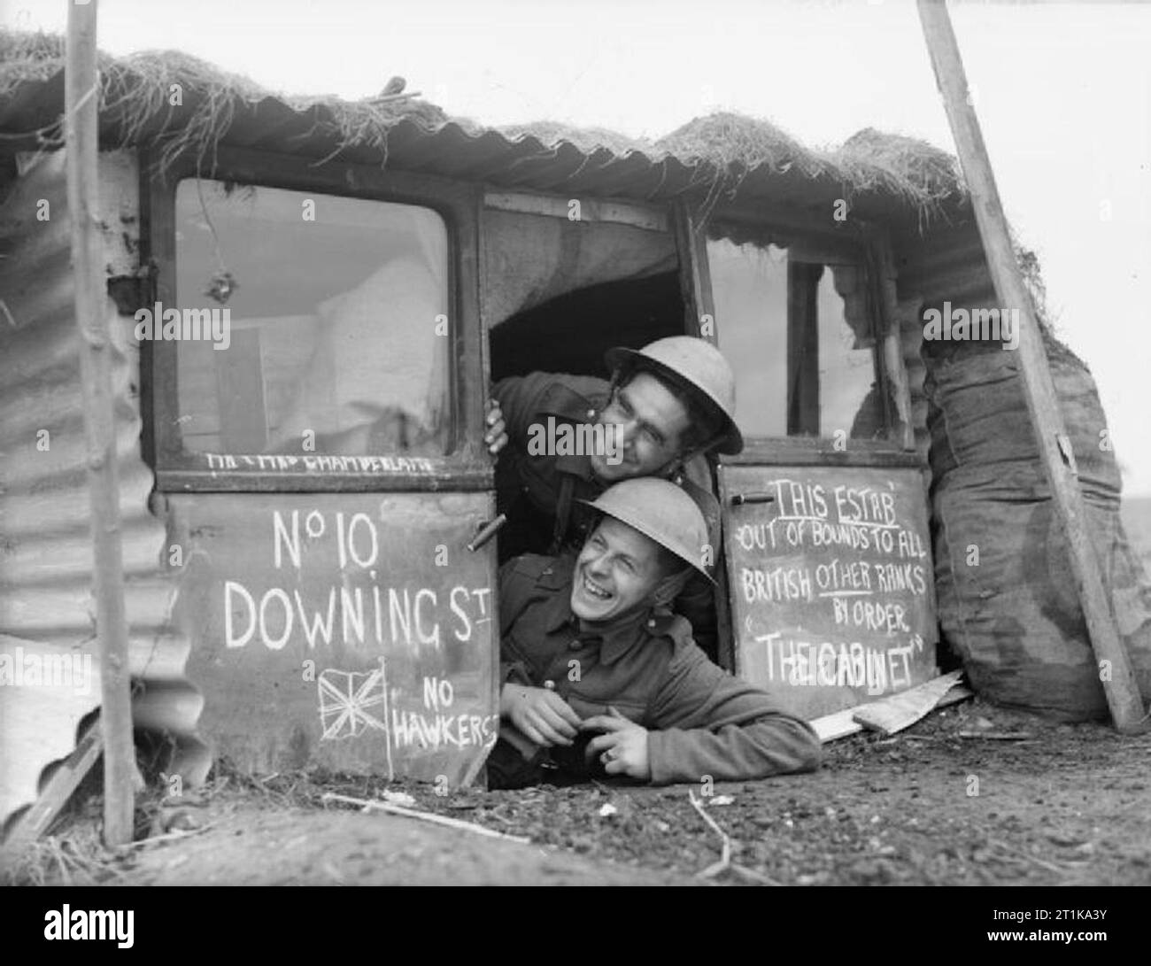 The British Army in France 1939 Two soldiers peer out from the entrance to their dugout, named '10 Downing Street', made from old car doors and corrugated iron, 28 November 1939. Stock Photo