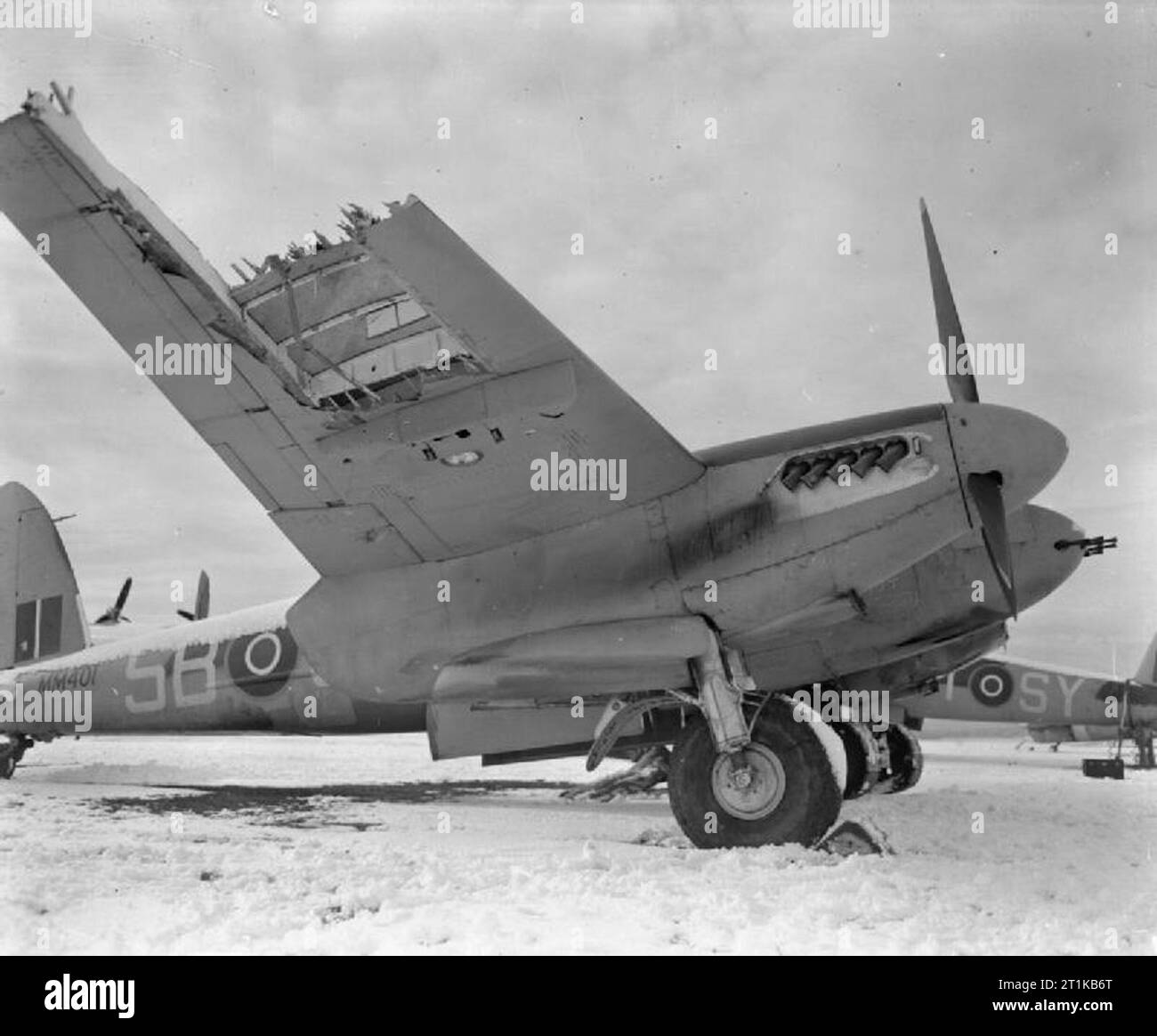 Royal Air Force- 2nd Tactical Air Force, 1943-1945. Severely damaged De Havilland Mosquito FB Mark VI, MM401 'SB-J', of No. 464 Squadron RAAF based at Hunsdon, Hertfordshire, parked at Friston Emergency Landing Ground, Sussex. The aircraft, flown by Squadron Leader A G Oxlade (pilot) and Flight Lieutenant D M Shanks (navigator), was hit by anti-aircraft fire while attacking a flying-bomb site in the Pas de Calais on 21 February 1944. The port engine was shattered, and the port undercarriage and most of the outer starboard wing was blown off. Despite the damage, the crew flew MM401 back and cra Stock Photo