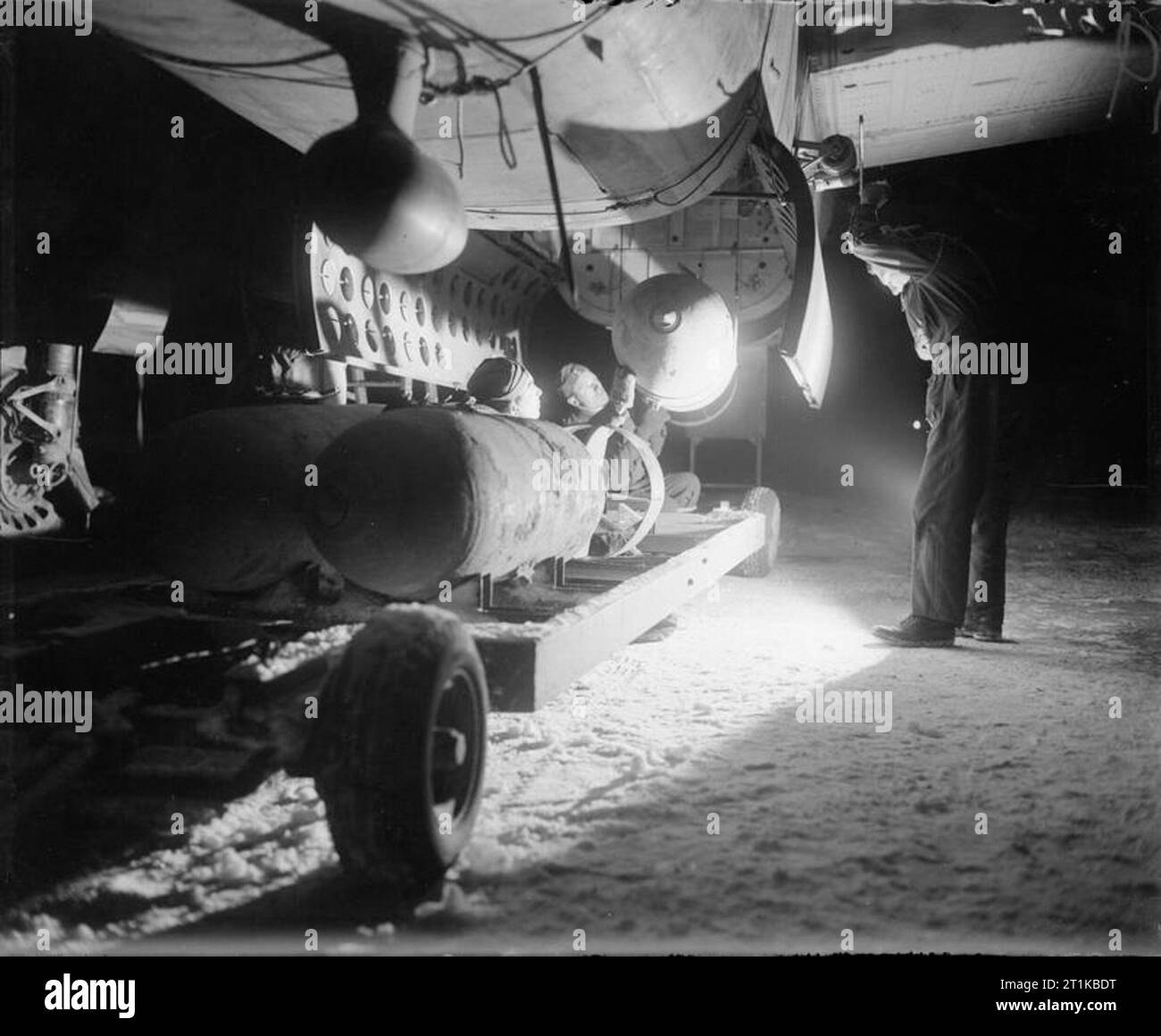 Royal Air Force- 2nd Tactical Air Force, 1943-1945. In the bitter cold and snow of a January night, armourers load four 1,000-lb MC bombs into the bomb-bay of a North American Mitchell of No. 139 Wing, No. 2 Group, for an early morning sortie from B58/ Melsbroek, Belgium. Stock Photo