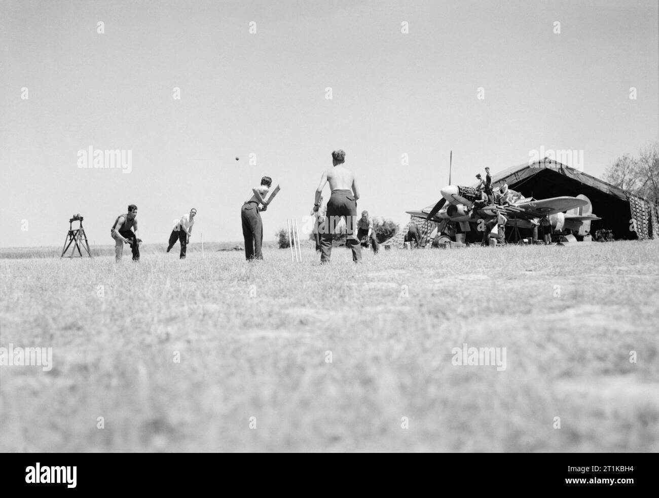 Royal Air Force- 2nd Tactical Air Force, 1943-1945. Ground crew enjoying a game of cricket as others service a Hawker Typhoon Mark IB of No. 174 Squadron RAF outside a canvas hangar at B5/Le Fresne Camilly, Normandy. Stock Photo