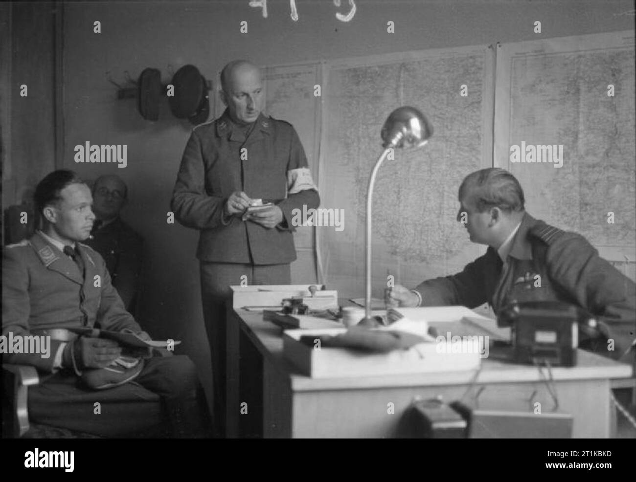 Royal Air Force- British Air Forces of Occupation, 1945. Wing Commander W W Russell (right), Commanding Officer of an RAF Disarmament Wing at Stavanger, Norway, conducts a morning conference with the Luftwaffe officer (left) in charge of prisoners who are disarming German aircraft at Sola airfield. A German interpreter stands in the middle taking notes and instructions. Stock Photo