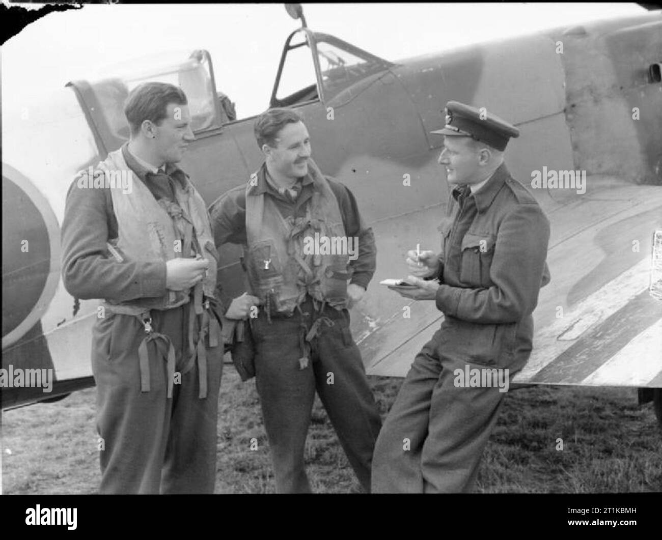Royal Air Force- Air Defence of Great Britain (adgb), 1943-1944. The OVERLORD DIVER Plan. Flying Officer E Topham (left) and Flight Lieutenant R Nash of No. 91 Squadron RAF give their reports to the Squadron Intelligence Officer, Flying Officer C Kember (right), at West Malling, Kent, after an anti-'Diver' patrol (sortie against flying bombs) over south-east England. Topham, a New Zealander, and Nash, from London, were among the top-scoring pilots in this work, shooting down 15 and 16.5 flying bombs respectively. Stock Photo