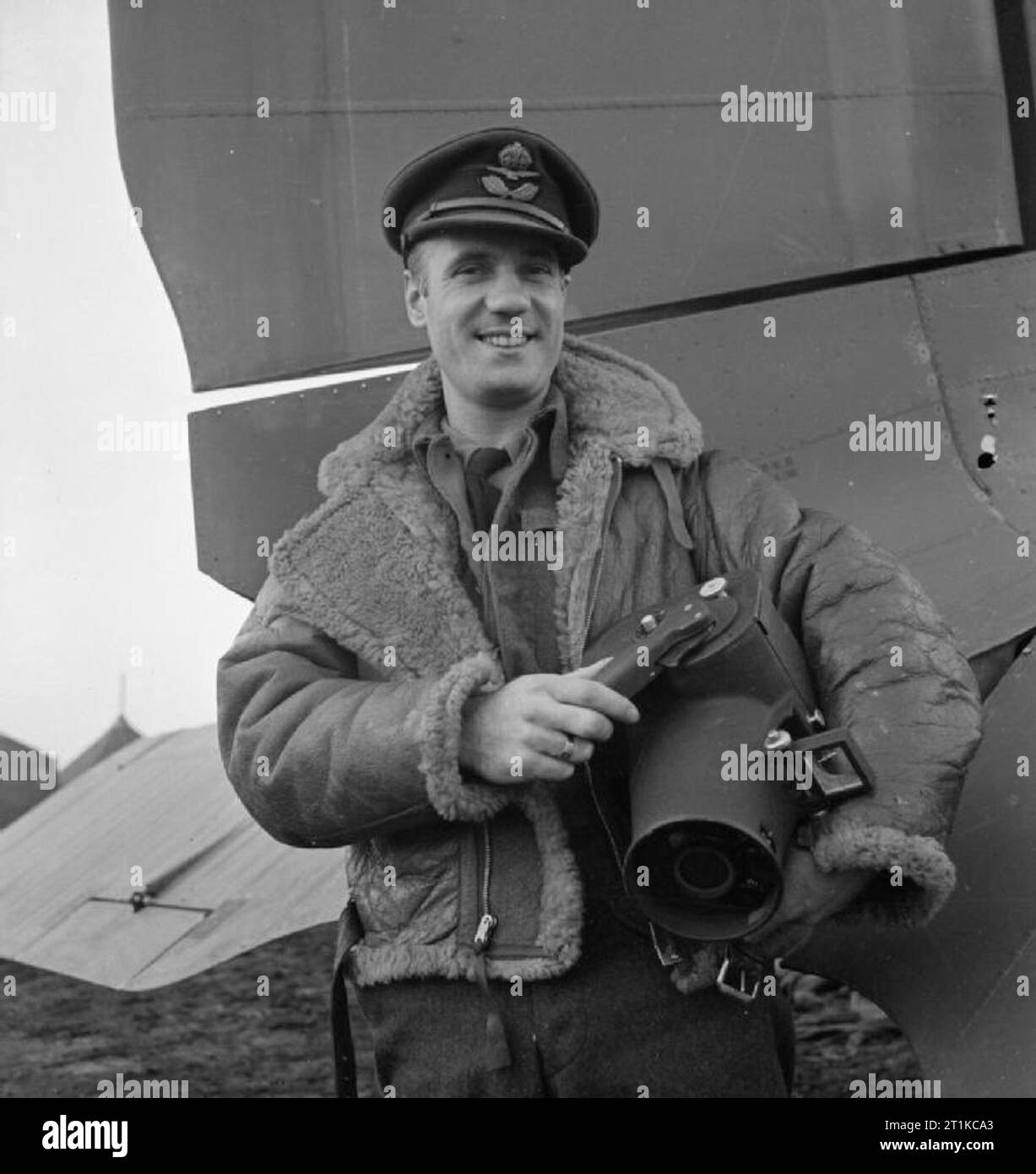 Royal Air Force- Italy, the Balkans and South-east Europe, 1942-1945. Flight Lieutenant L H Abbott, Air Ministry official photographer, on his return to Bari, Italy, after photographing Douglas Dakotas of No. 267 Squadron RAF over the Balkans. He is holding a Fairchild K-20 hand-held aerial camera, which has a 6-inch f.4.5 lens, which took 50 5'x 4' exposures on each roll of film. Examples of his work from this assignment can be seen under negative numbers CNA 3328, CNA 3333, CNA 3335 and CNA 3336. Like most of the photographers employed by the Air Ministry, Flt Lt Abbott was a professional pr Stock Photo