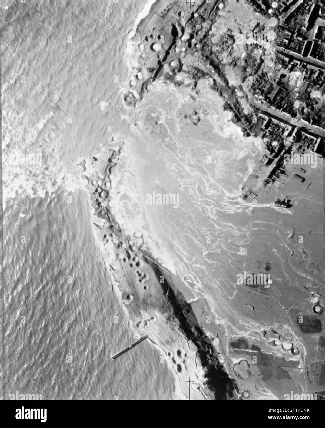 Royal Air Force Bomber Command, 1942-1945. Low-level vertical aerial photograph taken shortly after the daylight attack on the sea-wall of Walcheren Island, Holland, showing a breach in the wall at the most westerly tip of the island, caused by the extremely accurate bombing, being widened by the incoming high tide and inundating the village of Westkapelle (top right). Stock Photo