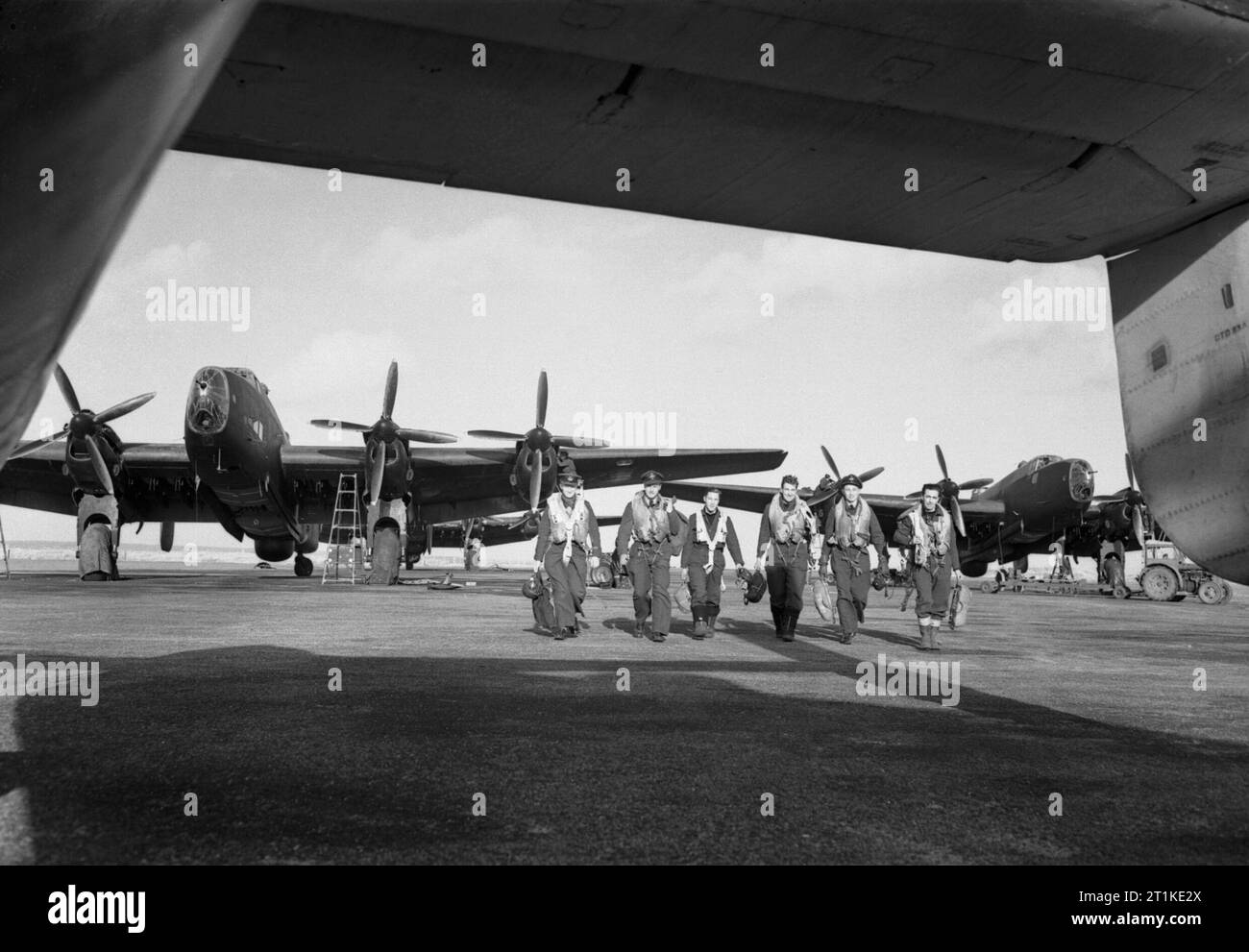 Aircrew and Handley Page Halifax Mk III bombers of No. 502 Squadron operating with RAF Coastal Command at Stornoway, in the Outer Hebrides, February 1945. A crew of No. 502 Squadron RAF walk to their aircraft past Handley Page Halifax Mark IIIs at Stornoway, Outer Hebrides. Stock Photo