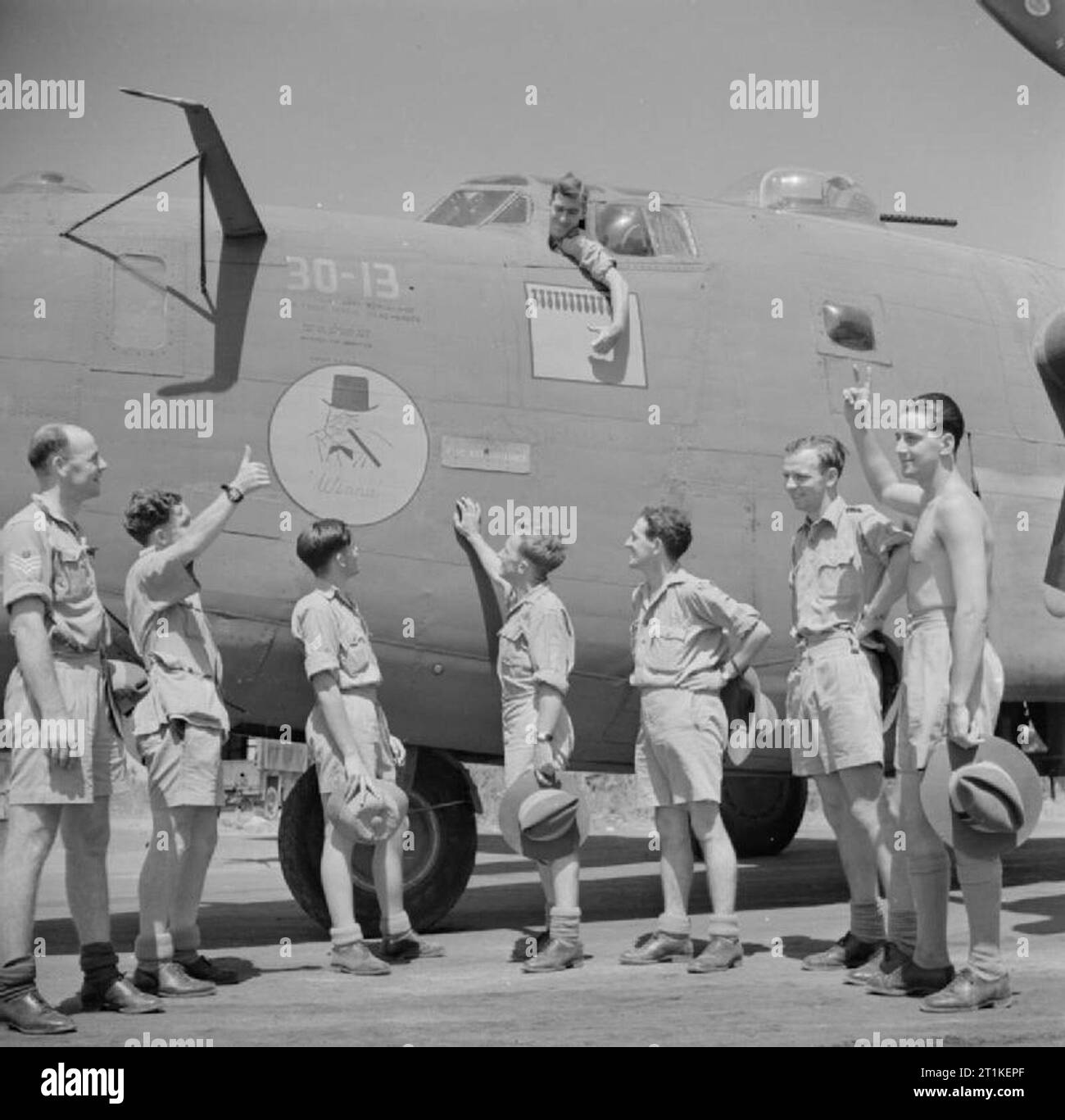 Royal Air Force Operations in the Far East, 1941-1945. The crew of 'Winnie' a Consolidated Liberator B Mark VI of No. 159 Squadron RAF based at Digri, India, salute the nose insignia on their aircraft. Sitting in the pilot's seat is Flying Officer Ken Alcorn of Perth, Australia, the captain The other crew members are, (left to right): Flight Sergeant Alex Baker of Wagga Wagga, NSW, (rear gunner) Warrant Officer Keith Weller of Thornleigh, NSW, (mid-gunner) Sergeant Ken Myers of Dagenham, Essex, (beam gunner) Flight Sergeant Errol Ford of Lithgow, NSW, (wireless operator) Flight Sergeant Ron Ew Stock Photo