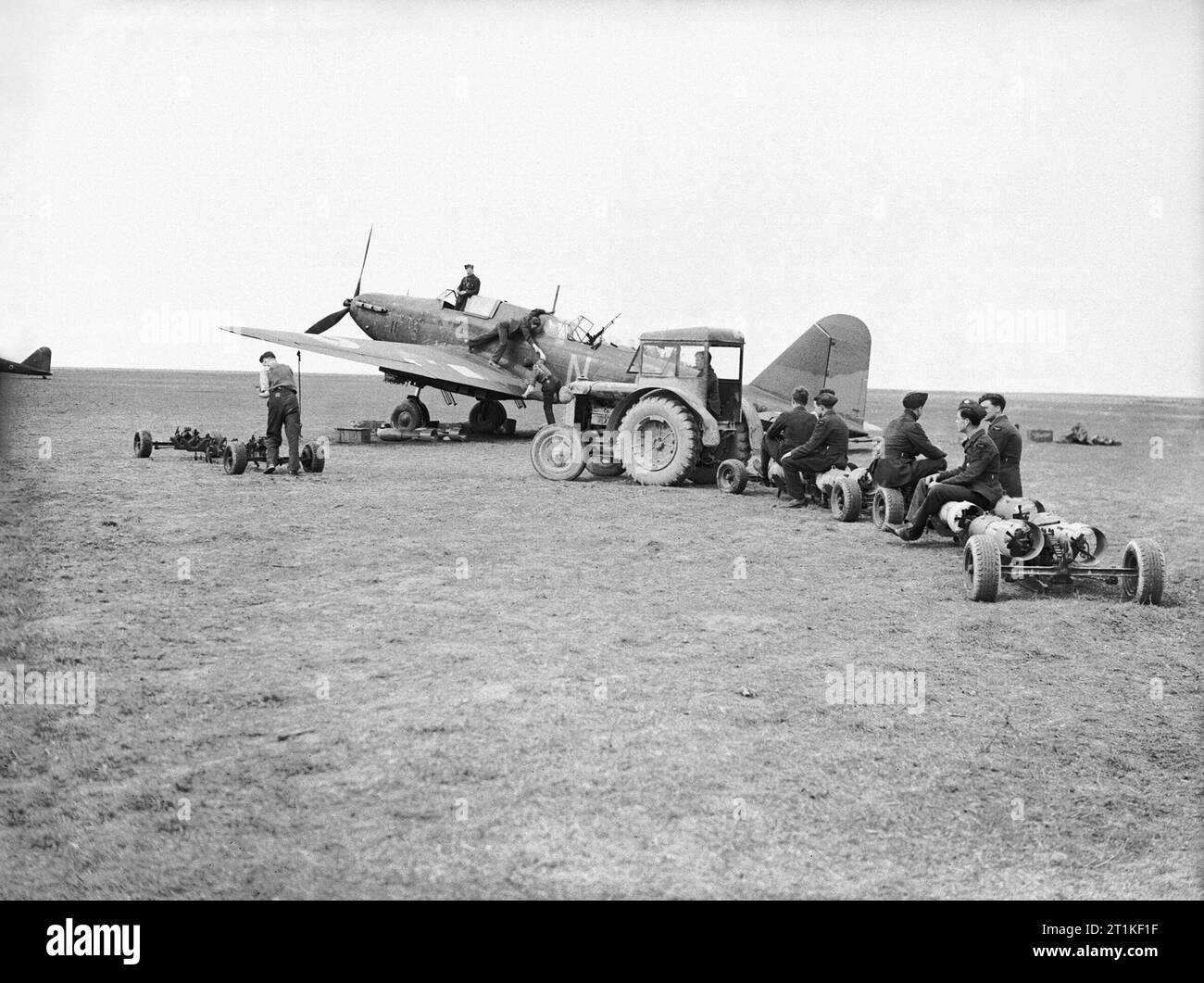 Royal Air Force- France, 1939-1940. Bomb-trolleys loaded with 250-lb GP bombs and attendant armourers being towed out by tractor to Fairey Battles at Betheniville prior to a sortie to the bombing practice range at Moronvilliers. Behind them, Battle, K9408 'PM-N', of No. 103 Squadron RAF is prepared for a flight. Stock Photo