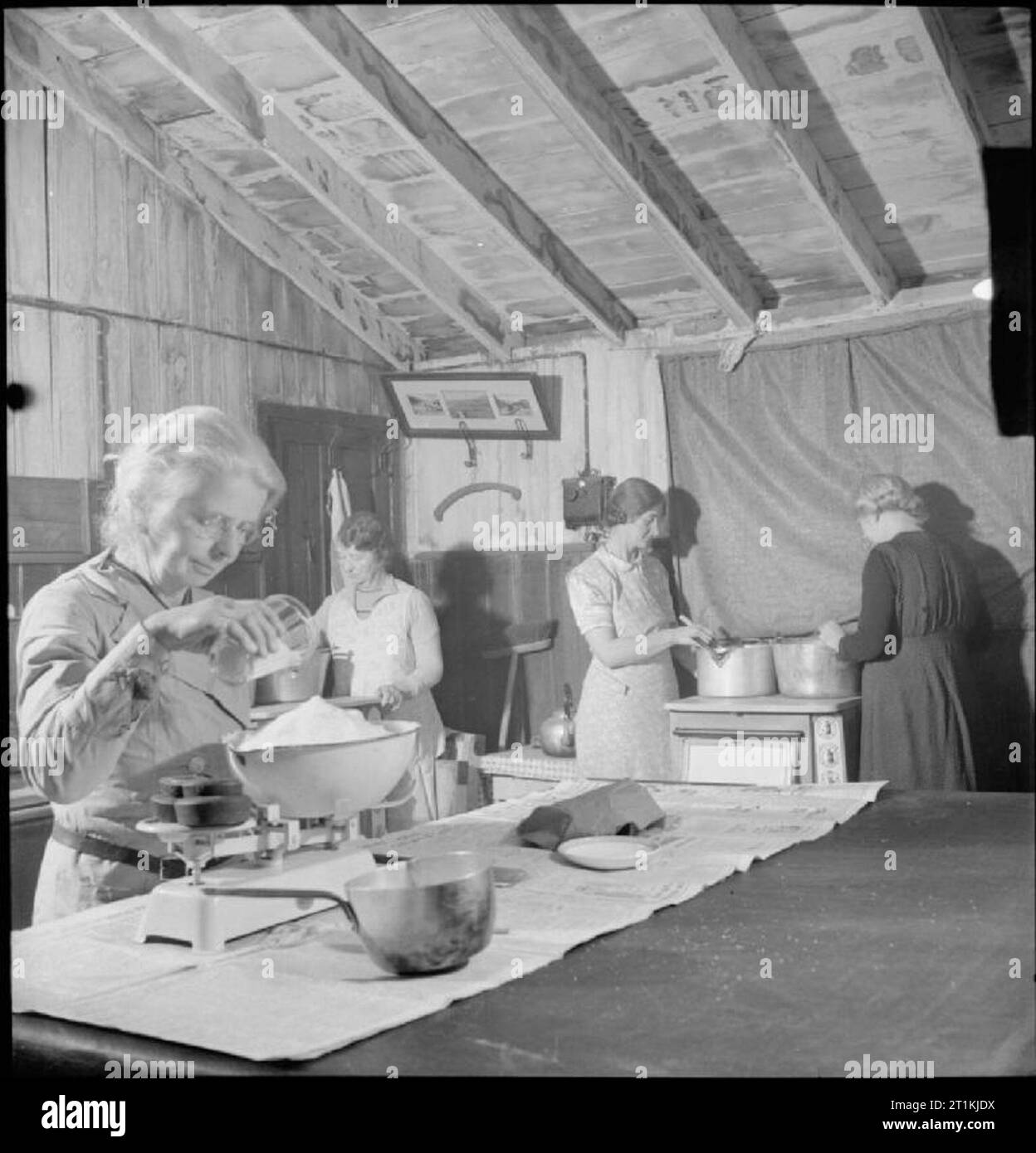 Community Gardening- Wartime Food Production at Rowney Green, Worcestershire, England, UK, 1943 Women's Institute members Mrs Nutting, Mrs Bull, Mrs Harborne and a colleague make jam in the Peace Hall (an army hut converted into a village hall) at Rowney Green, Worcestershire. The fruit was provided by people in the village, from their own gardens, and the sugar came from the government. According to the original caption, this centre has made nearly a ton and three-quarters of jam in the three seasons since the scheme began. Stock Photo